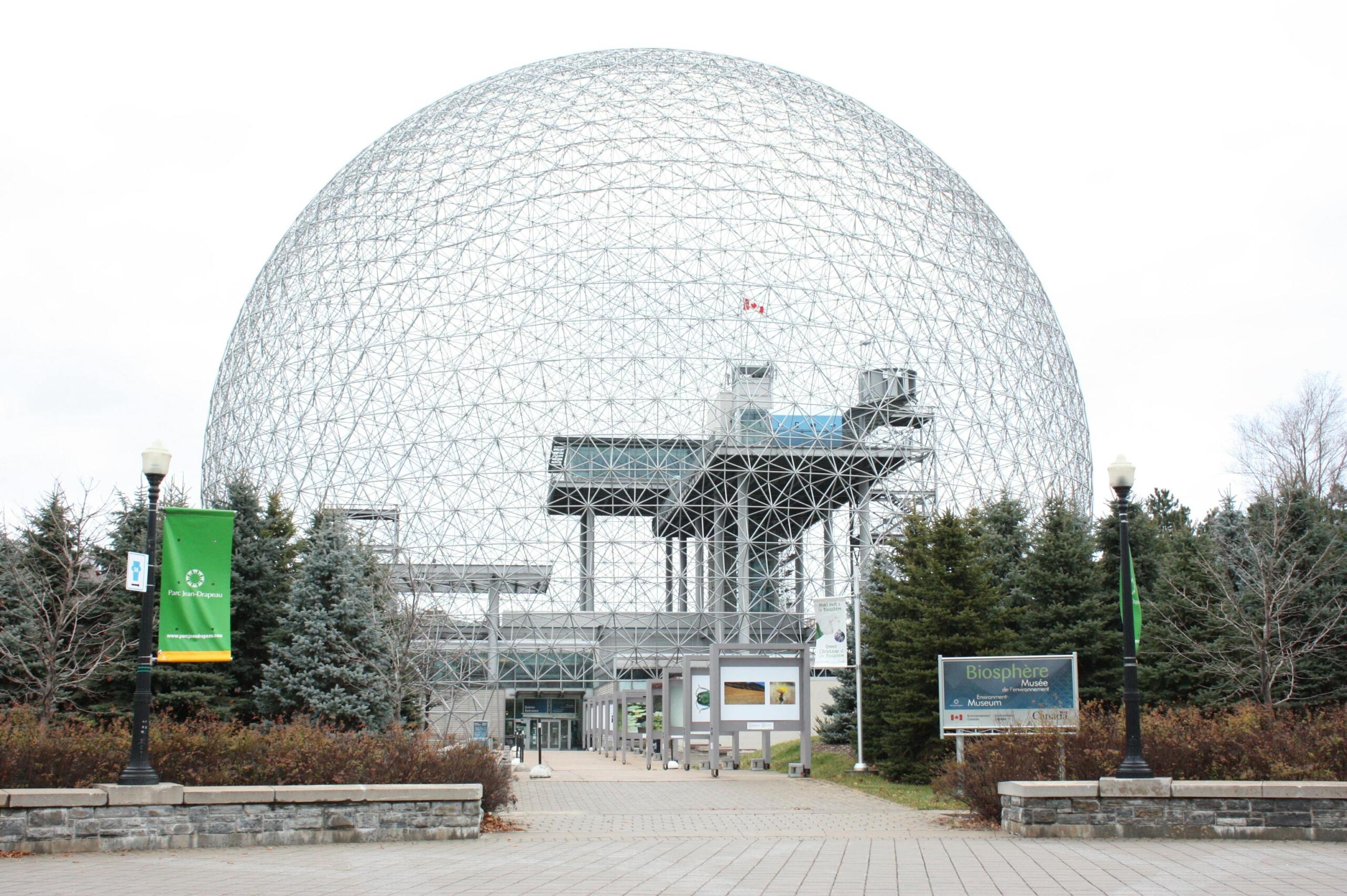Interior view of the Montréal Biodôme featuring a lush indoor ecosystem with tropical plants, trees, walking paths, and naturalistic habitats designed to recreate diverse environments.
