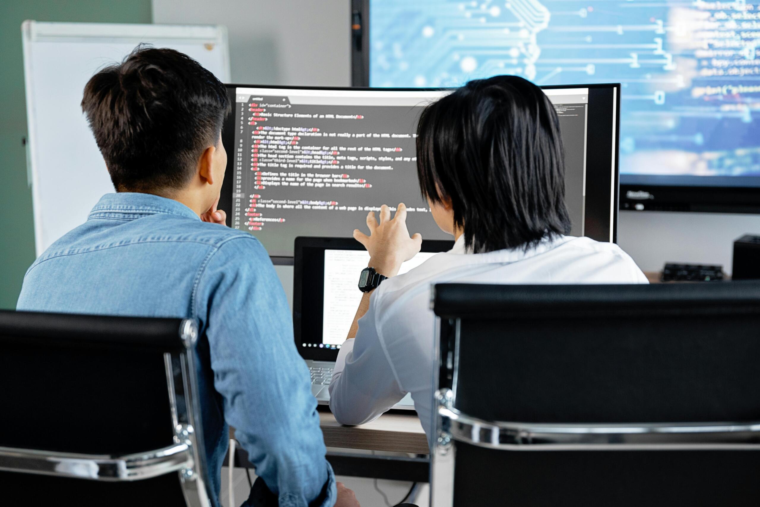 two professionals sit at a computer working and problem solving.
