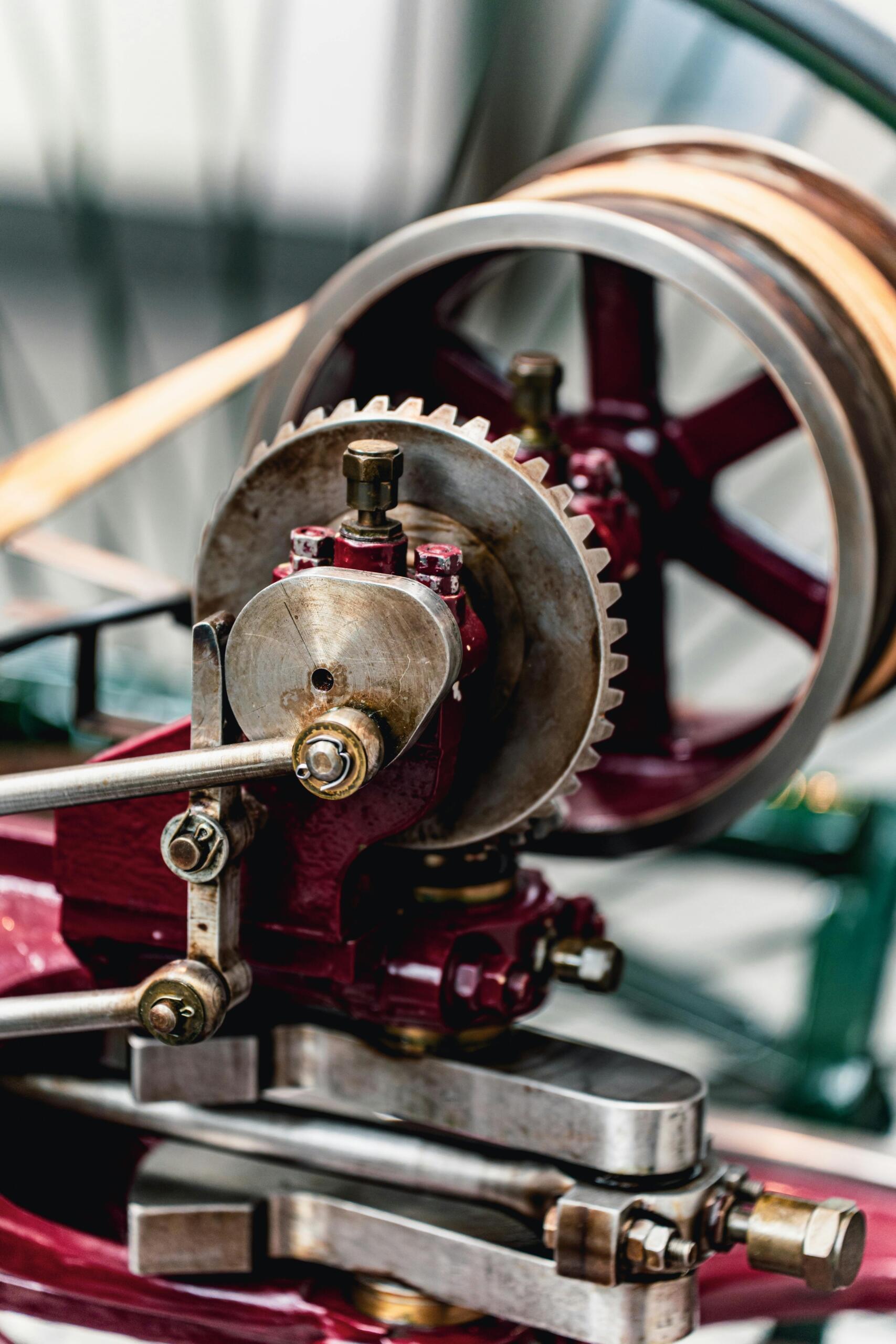 A mechanical system composed of interconnected gears, shafts, and rotating components works together to transfer motion and force. The metal parts fit together precisely, demonstrating how mechanical energy can be transmitted through a machine.