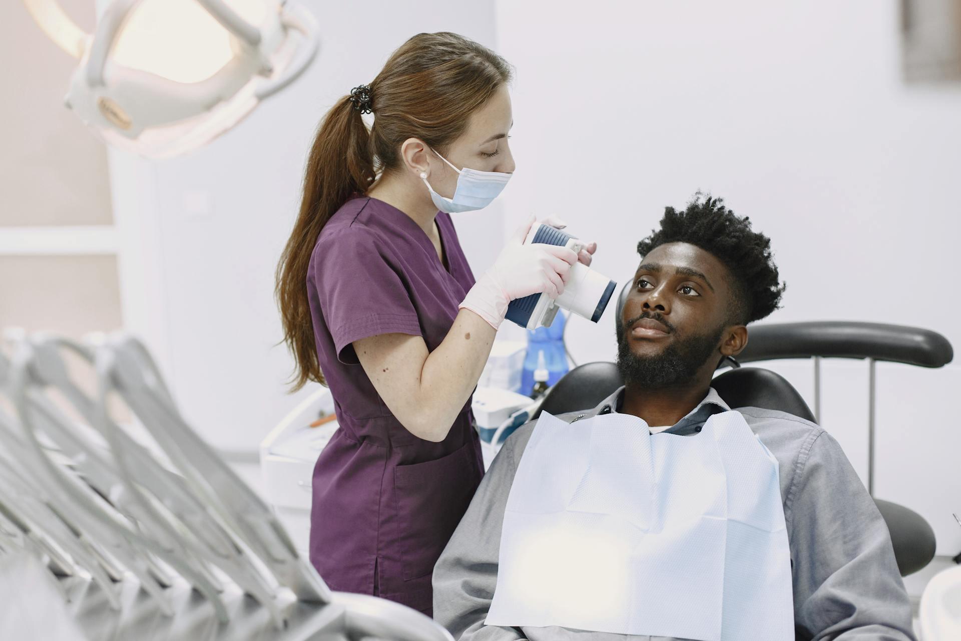 Dental assistant taking an x-ray of a patient's teeth with a compact X-ray camera