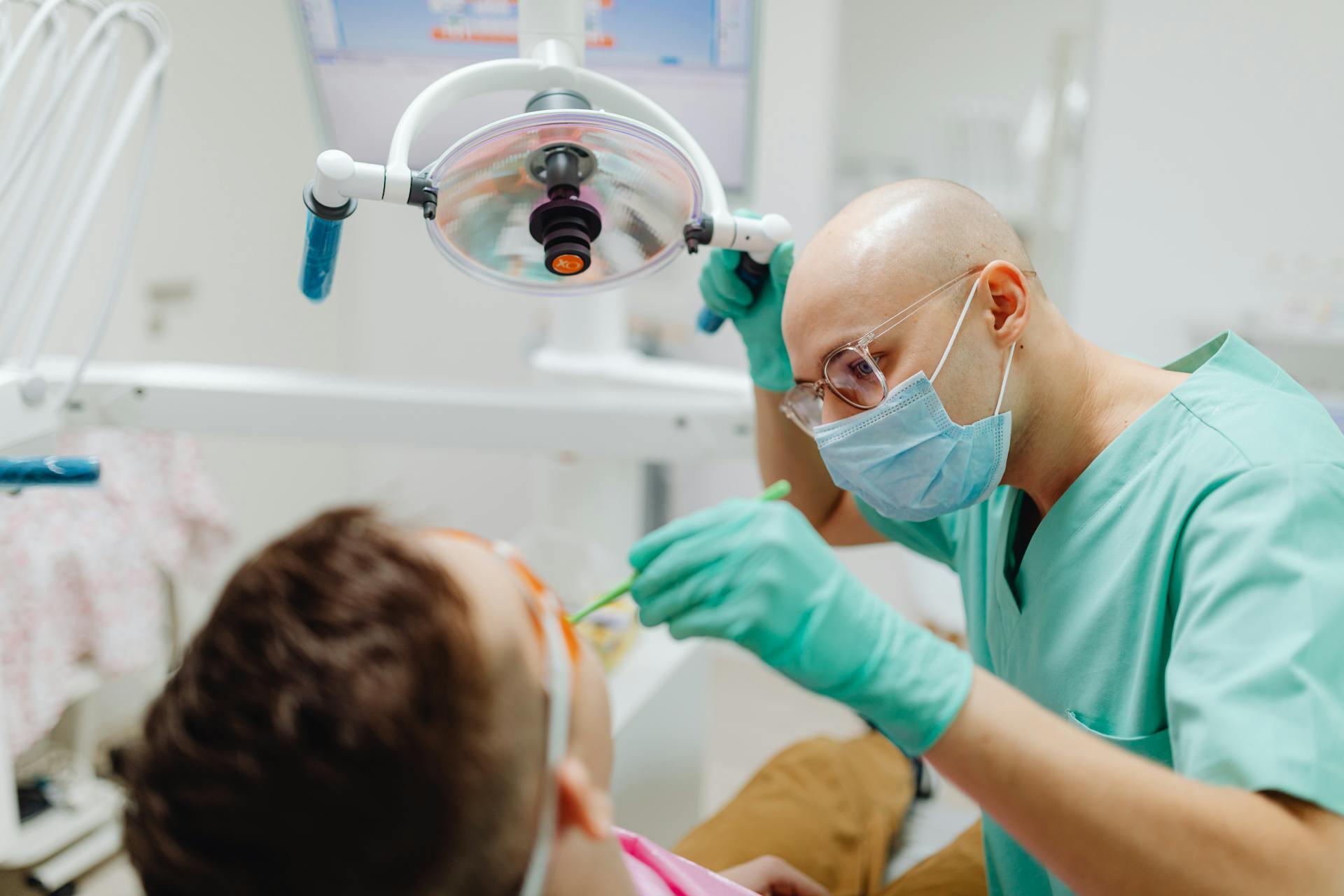 dentist inspecting patient's teeth while adjusting the overhead light on an arm