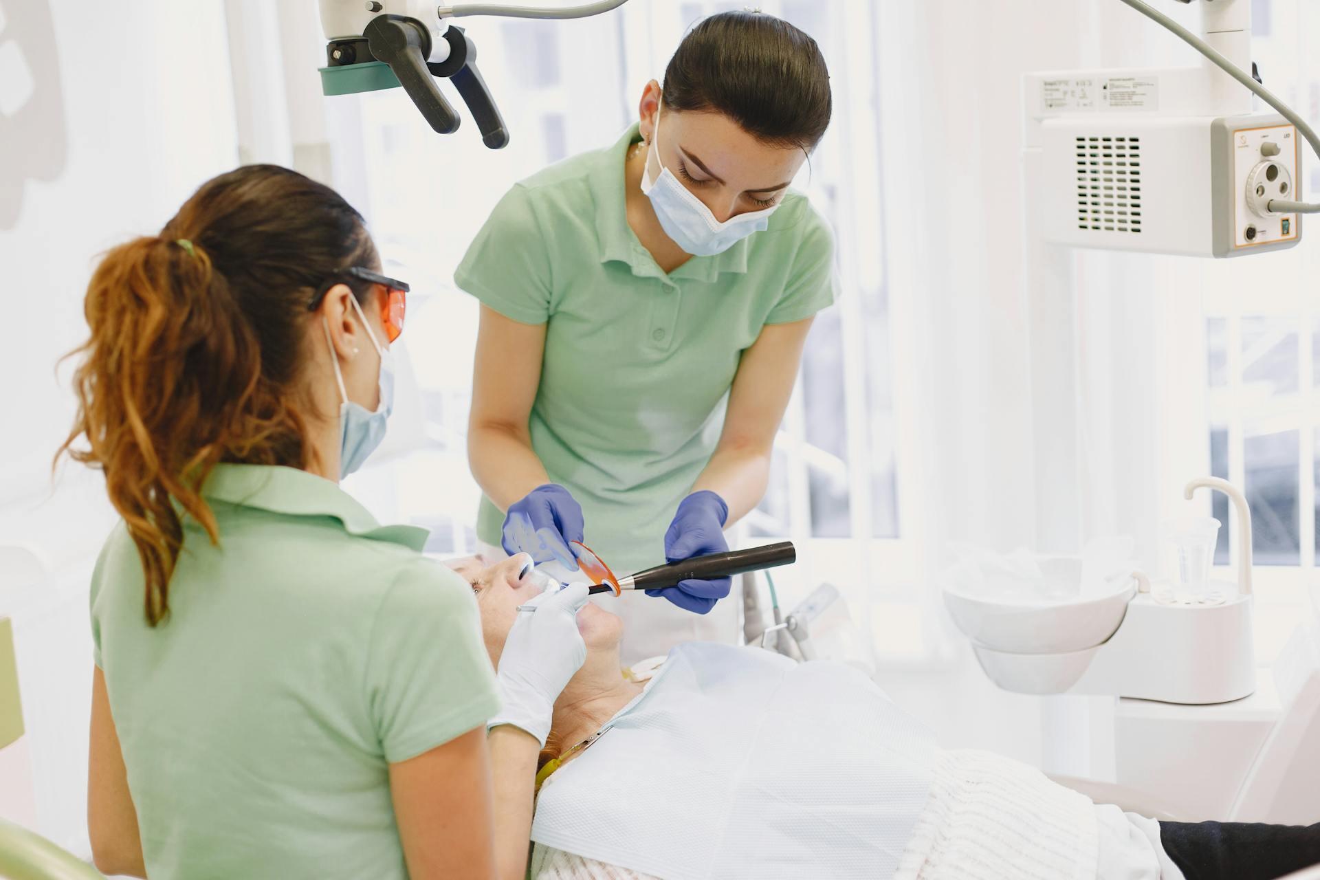 a dentist and dental assistant provide dental services to a patient reclined in a dentist chair