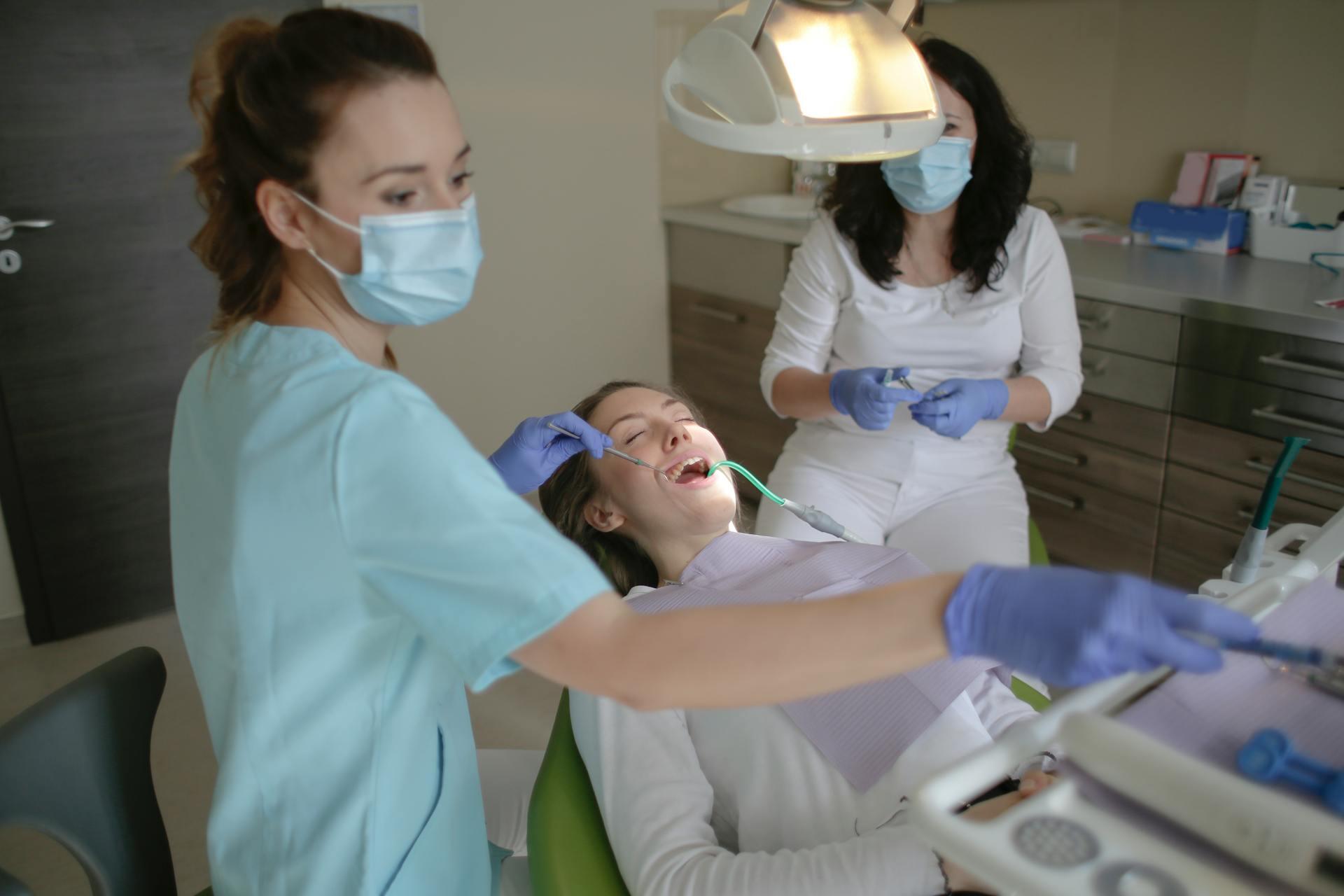 A dentist and an assistant clean a patient's teeth