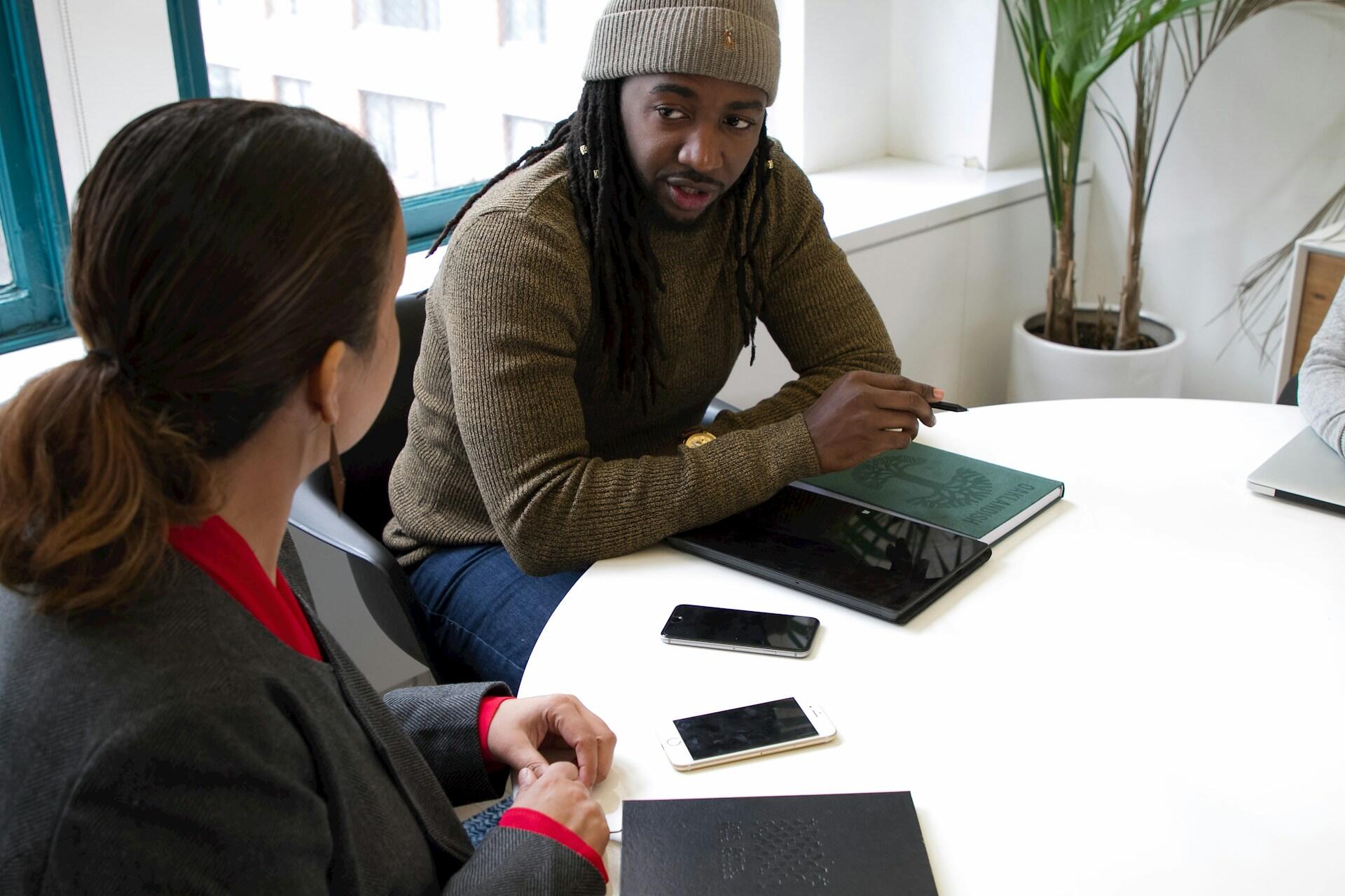 Three individuals seated at a table, each using a laptop, engaged in a collaborative work session.