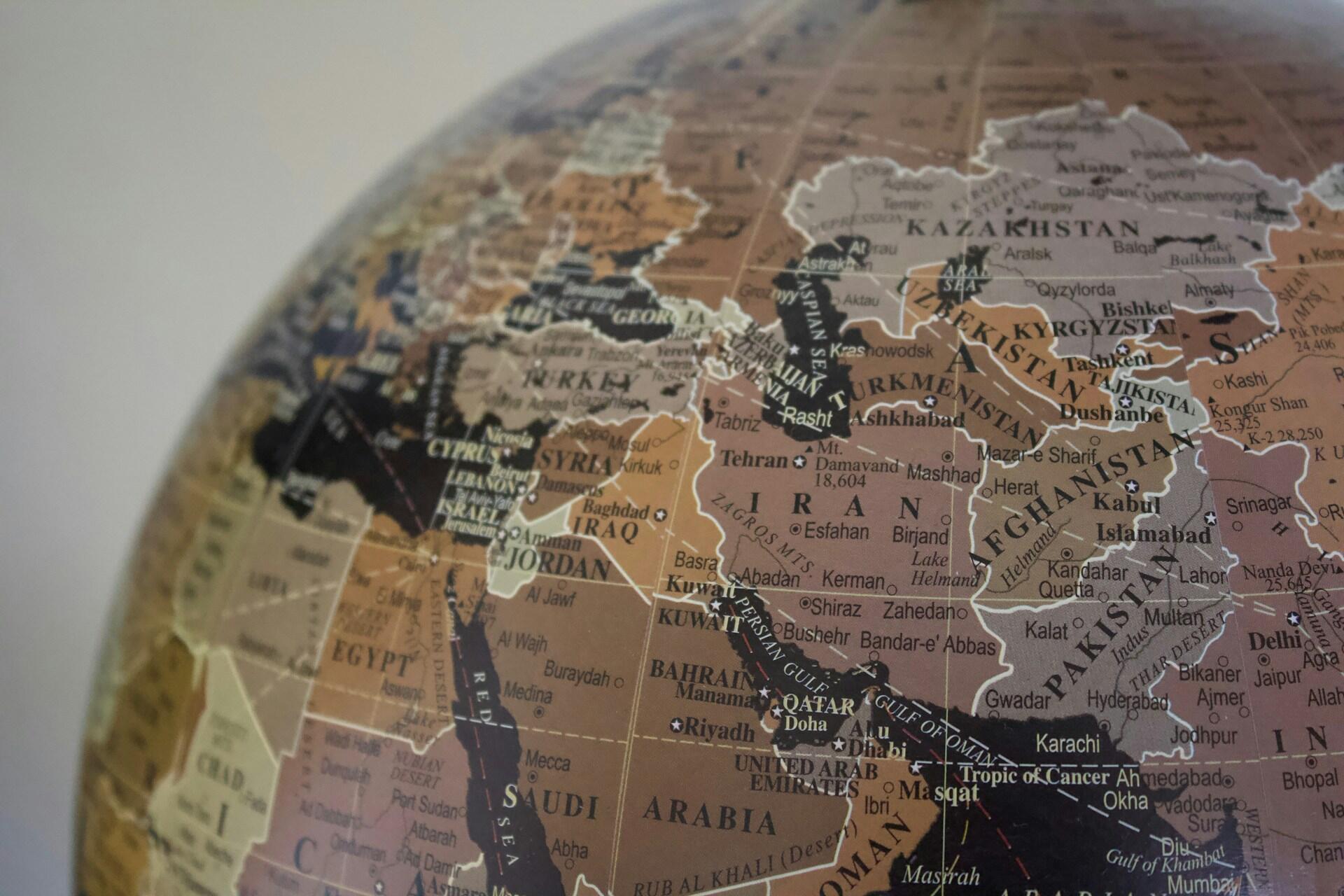 Close-up of a globe showing countries of the Middle East and Central Asia, including Saudi Arabia, Iran, Afghanistan, and Pakistan.