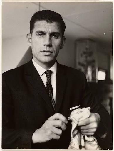 Black-and-white portrait of Gerard Reve, influential Dutch writer, wearing a dark suit and holding a cloth.