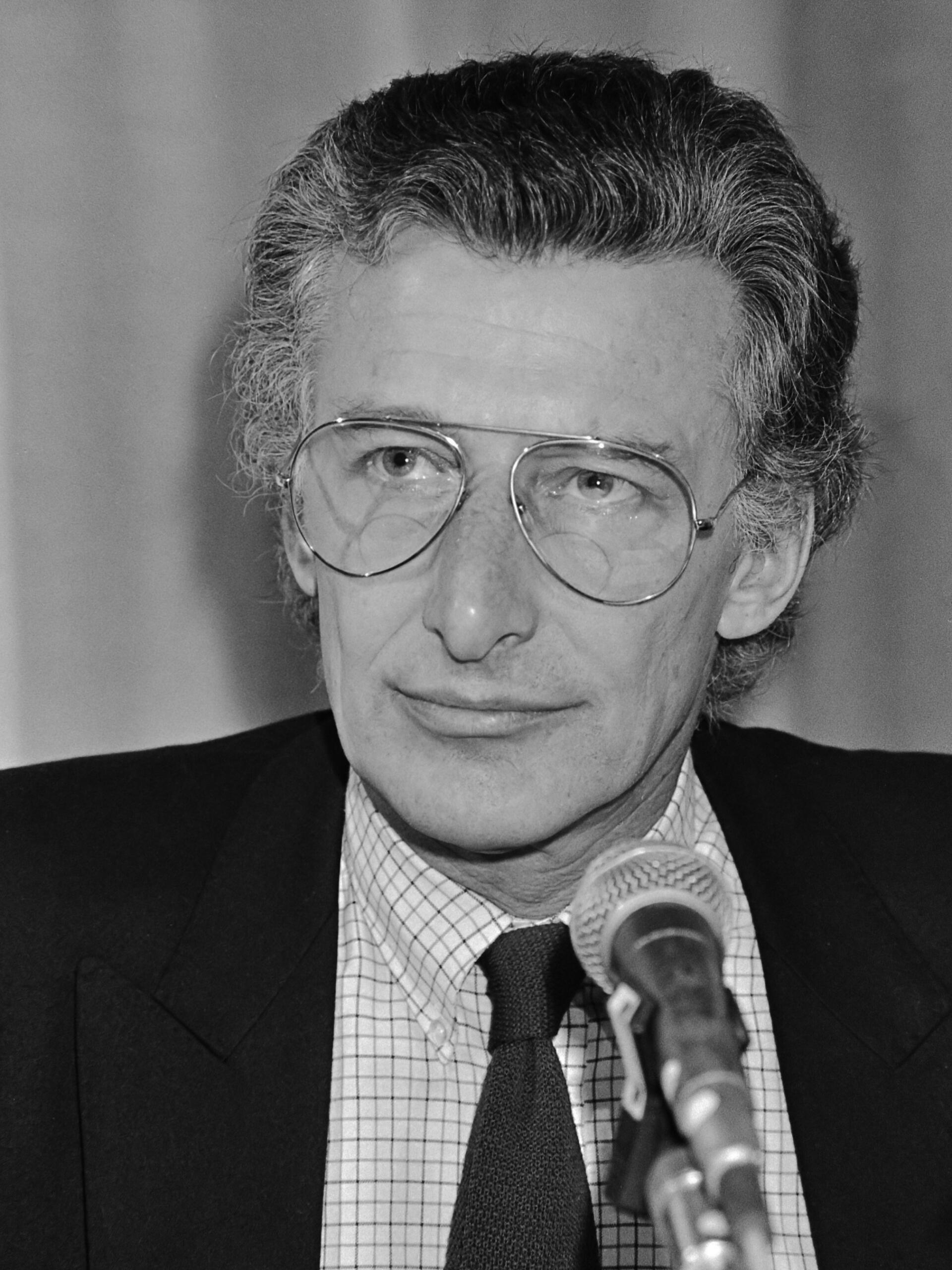Black-and-white portrait of Harry Mulisch, acclaimed Dutch author, speaking at a microphone during a public event.