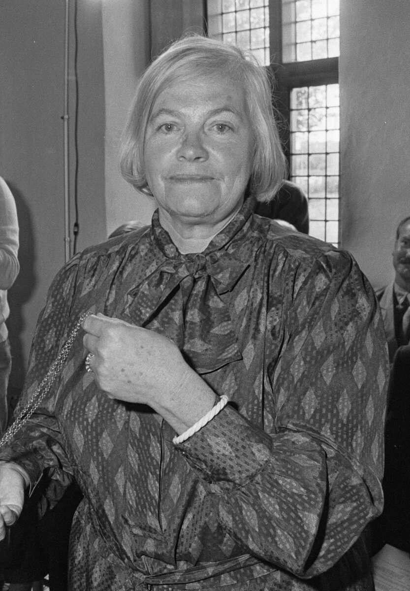 Portrait of Hella S. Haasse, renowned Dutch novelist, standing indoors in a patterned blouse.