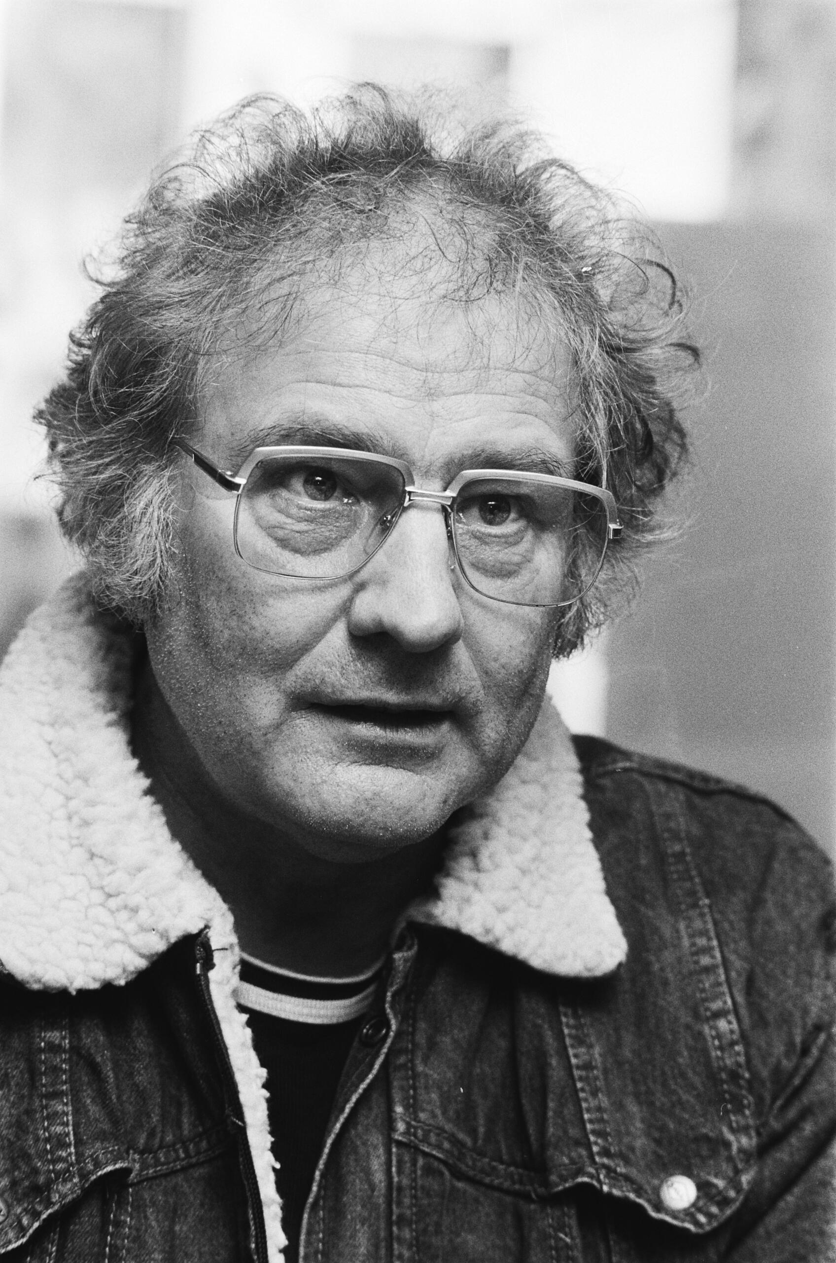 Portrait of Jan Wolkers, Dutch novelist and artist, wearing glasses and a denim jacket with a shearling collar.