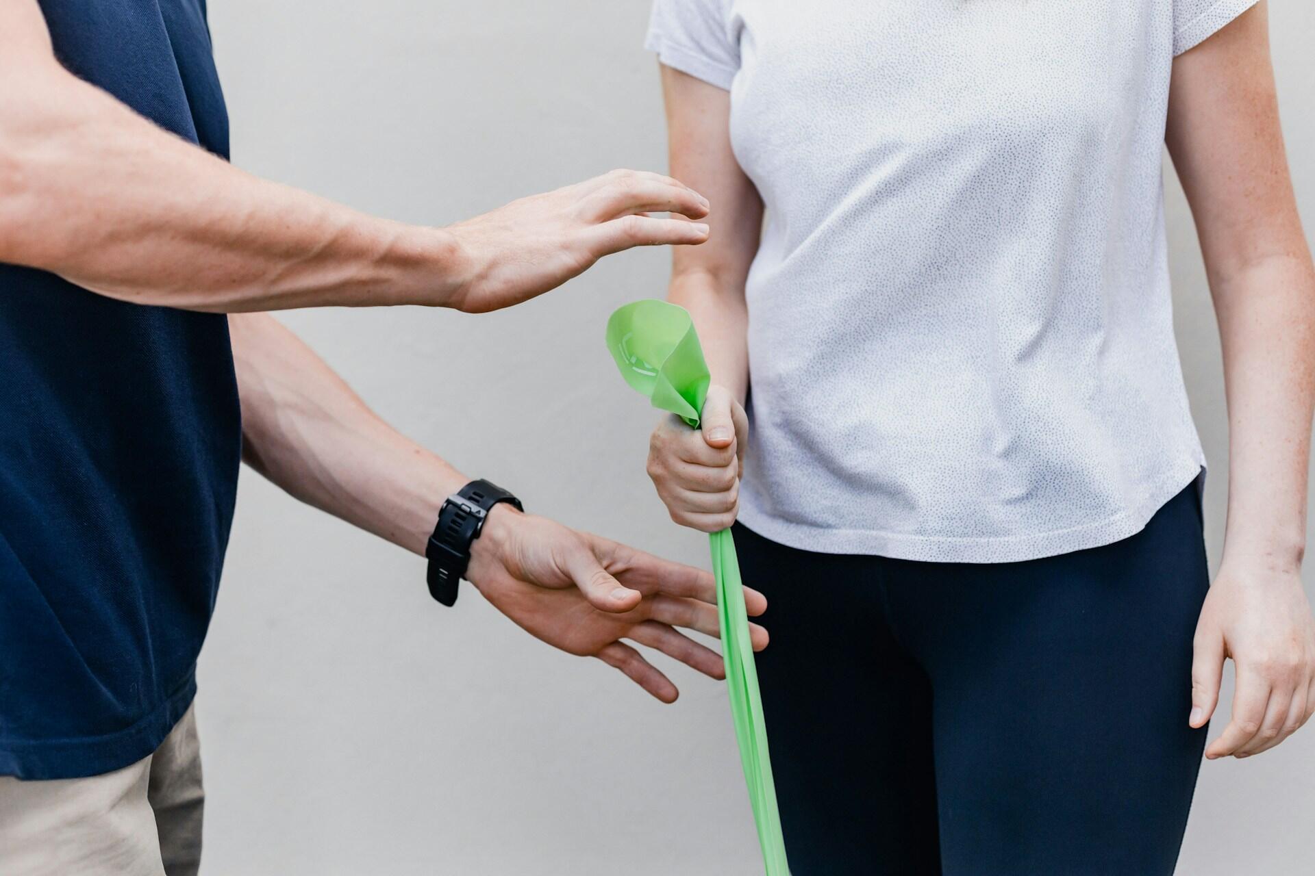 A man and woman hold a green stick together, smiling and engaged in conversation.