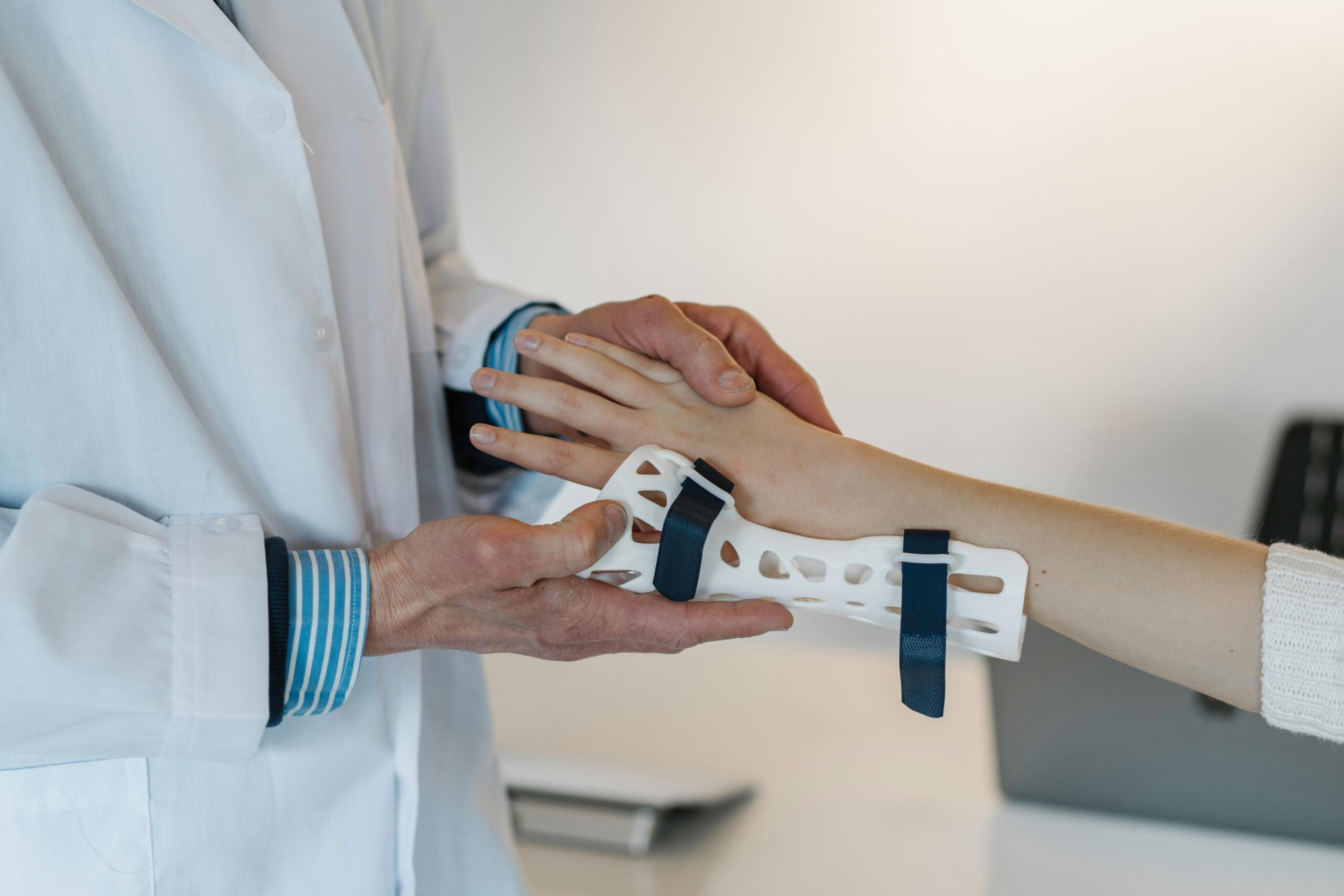 Doctor adjusting a white wrist brace with dark straps on a patient's arm in a clinical setting.