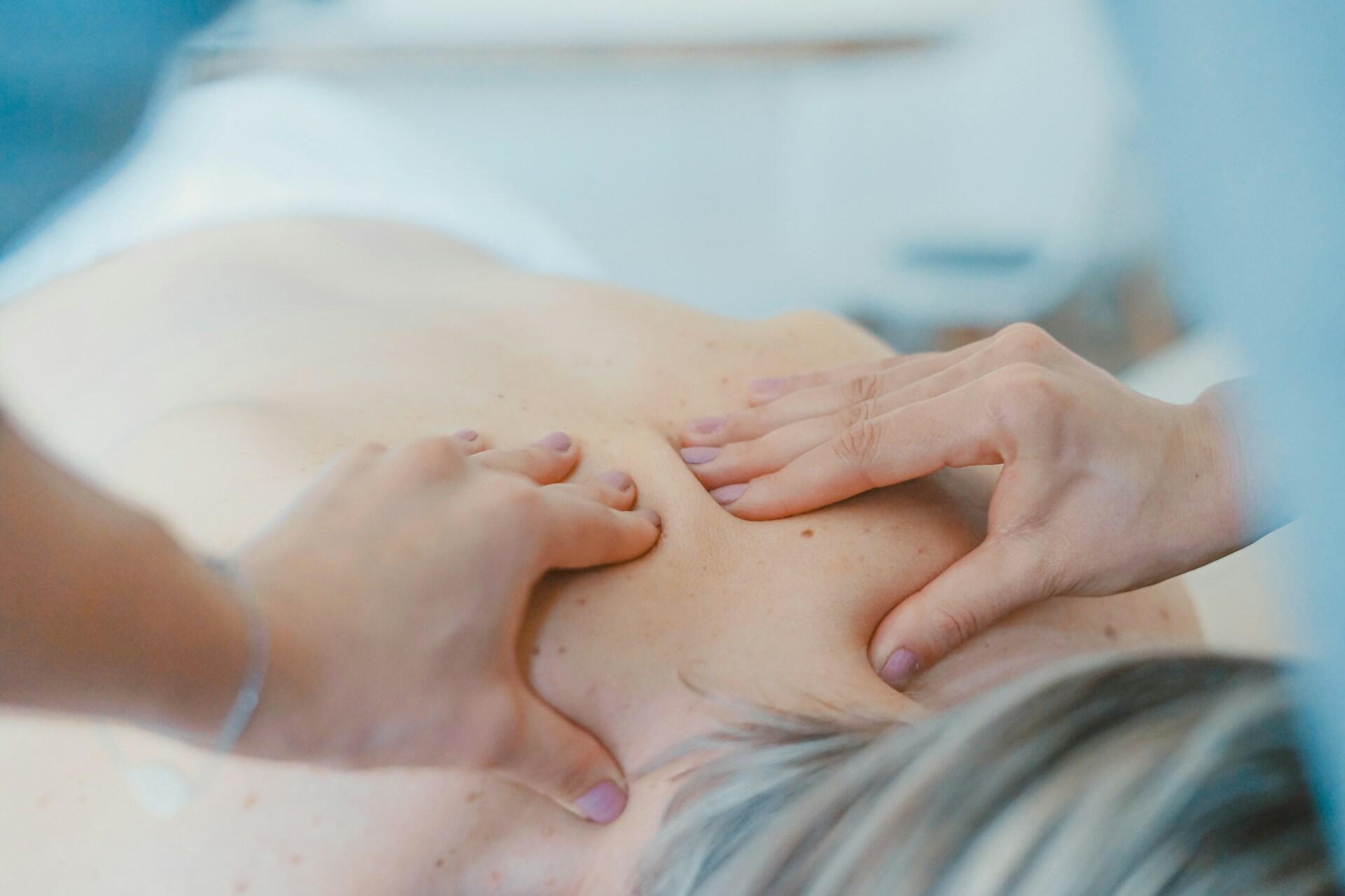 A woman receiving a back massage in a serene room, surrounded by calming decor and soft lighting.