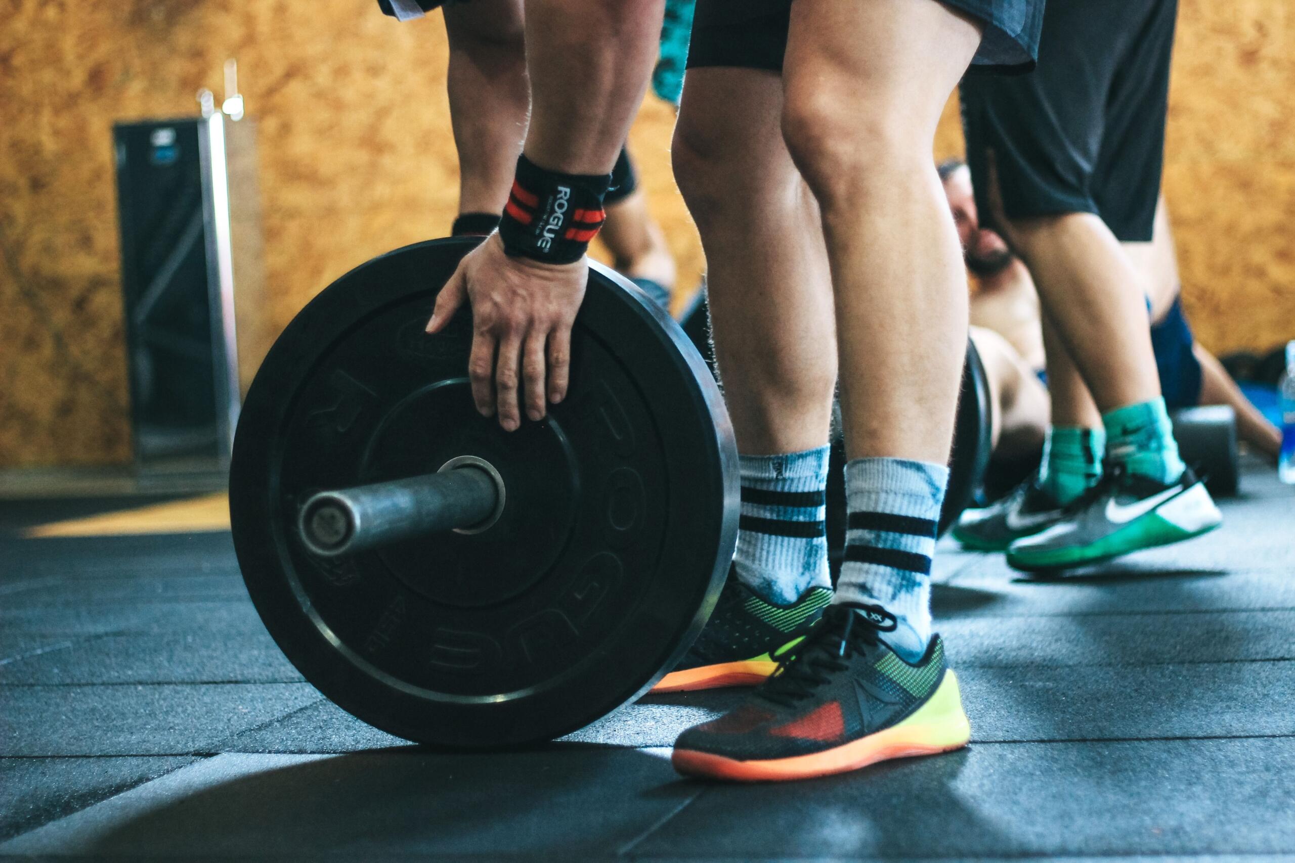 A man secures weight plates onto a dumbbell, tightening the collar before a strength training workout in a well-equipped gym.