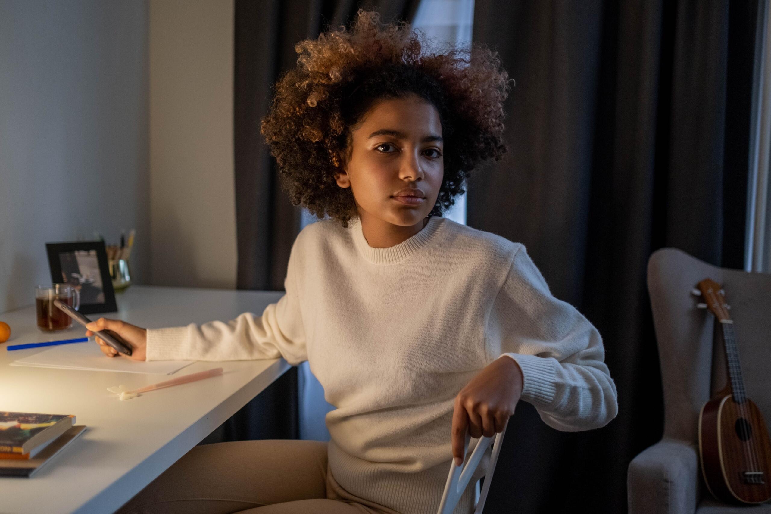Young woman sitting at a desk, contemplating her future.