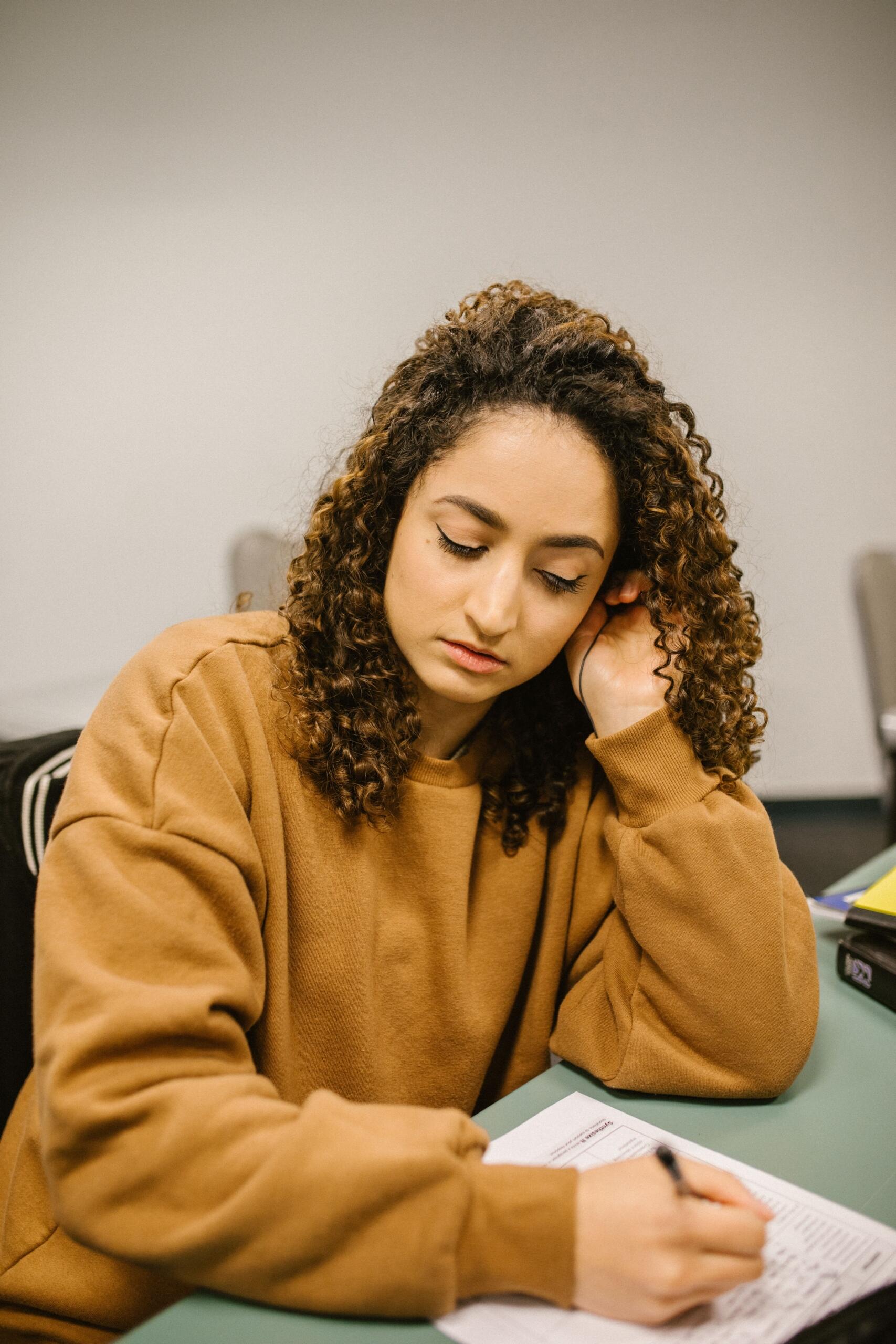 An older student writes on a page, focused on her work.