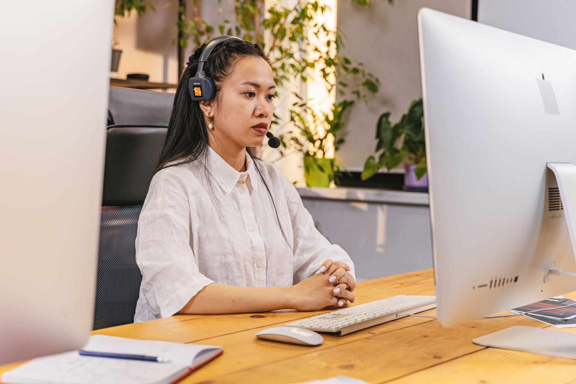 test candidate sitting at a desk, wearing a headset headphones and microphone and looking at their computer screen