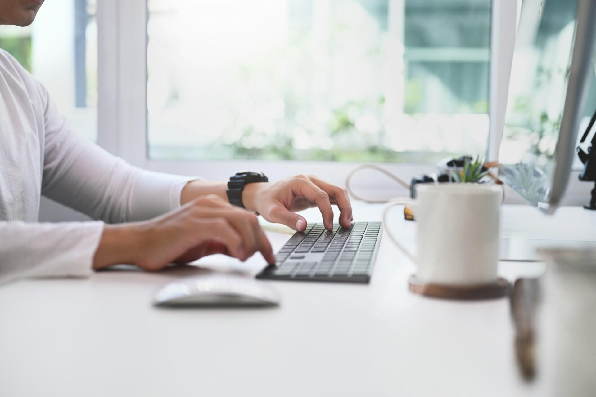 a person typing on a computer keyboard in a bright, clean-looking room