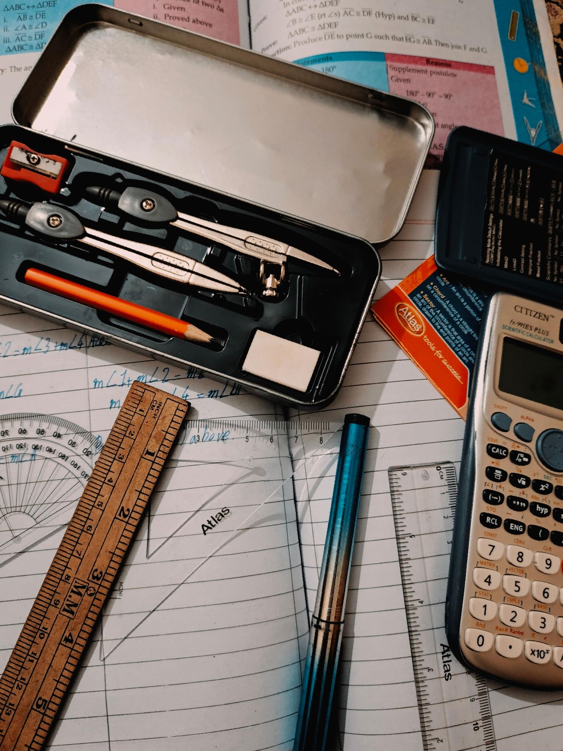 a math textbook and notebook opened up covered with rulers, a geometry set, and scientific calculator. Source: Ijaz Ahmed.