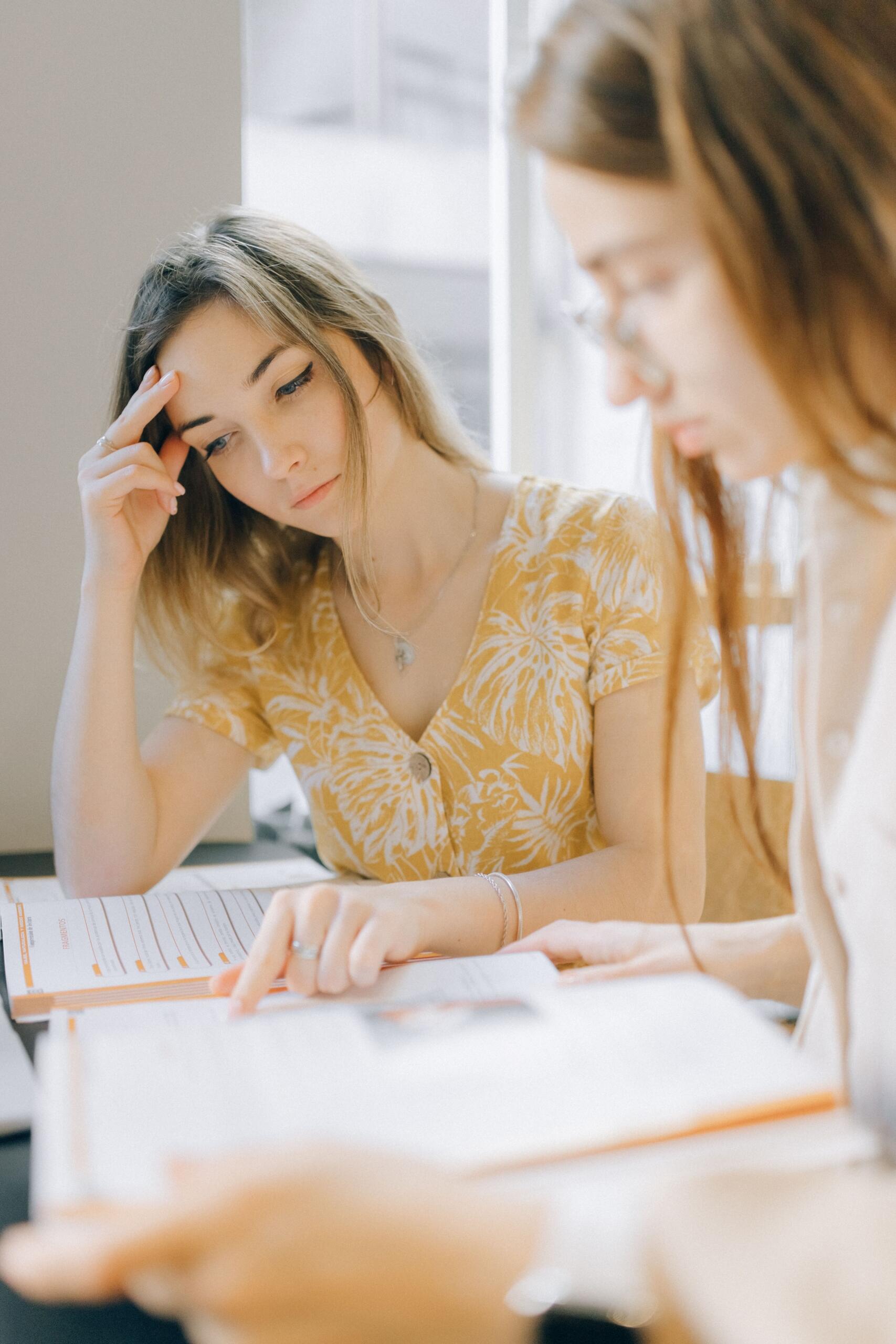 a teacher and a young woman review notes to study for a test.