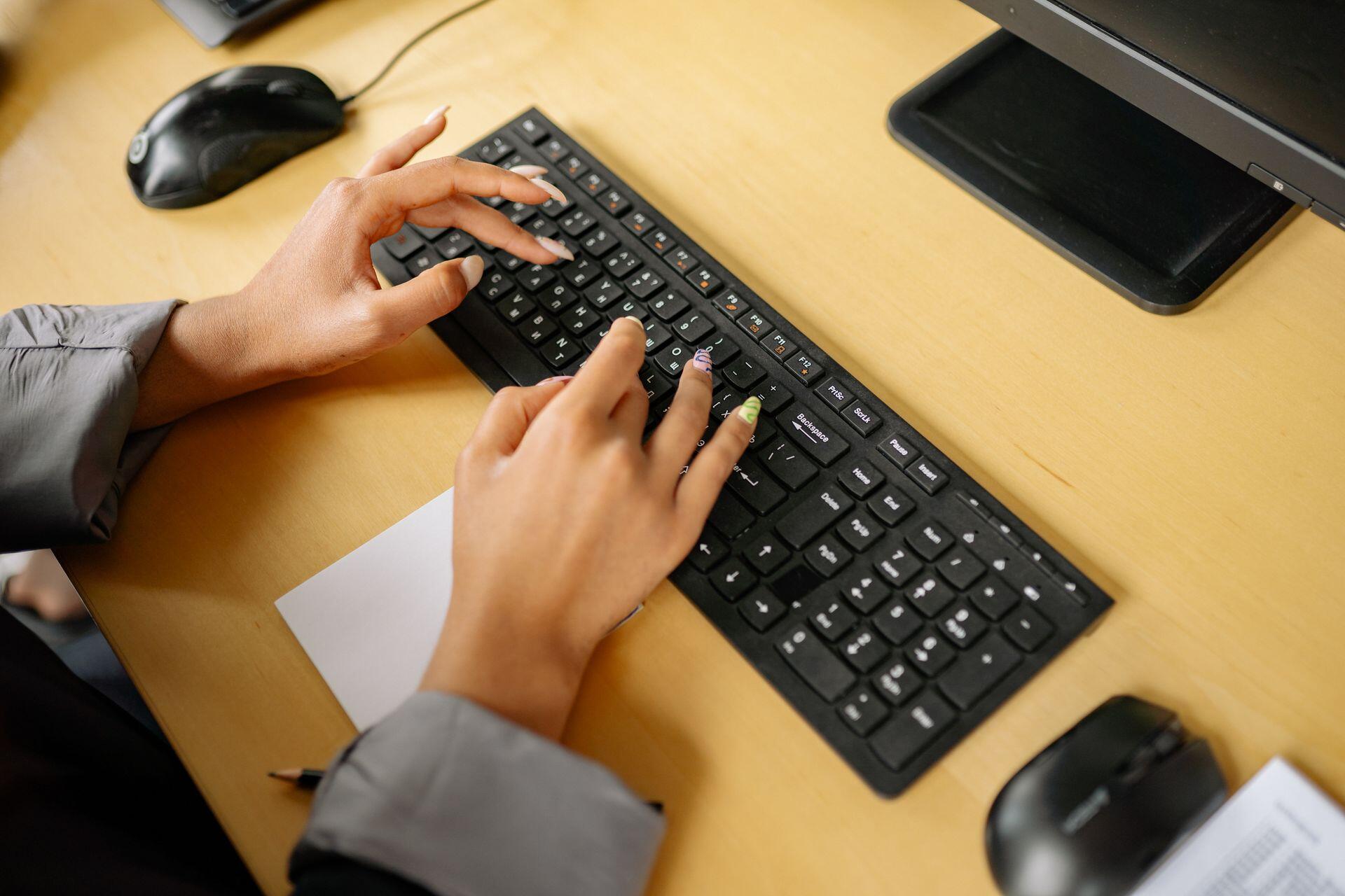 person typing on a keyboard on a desktop