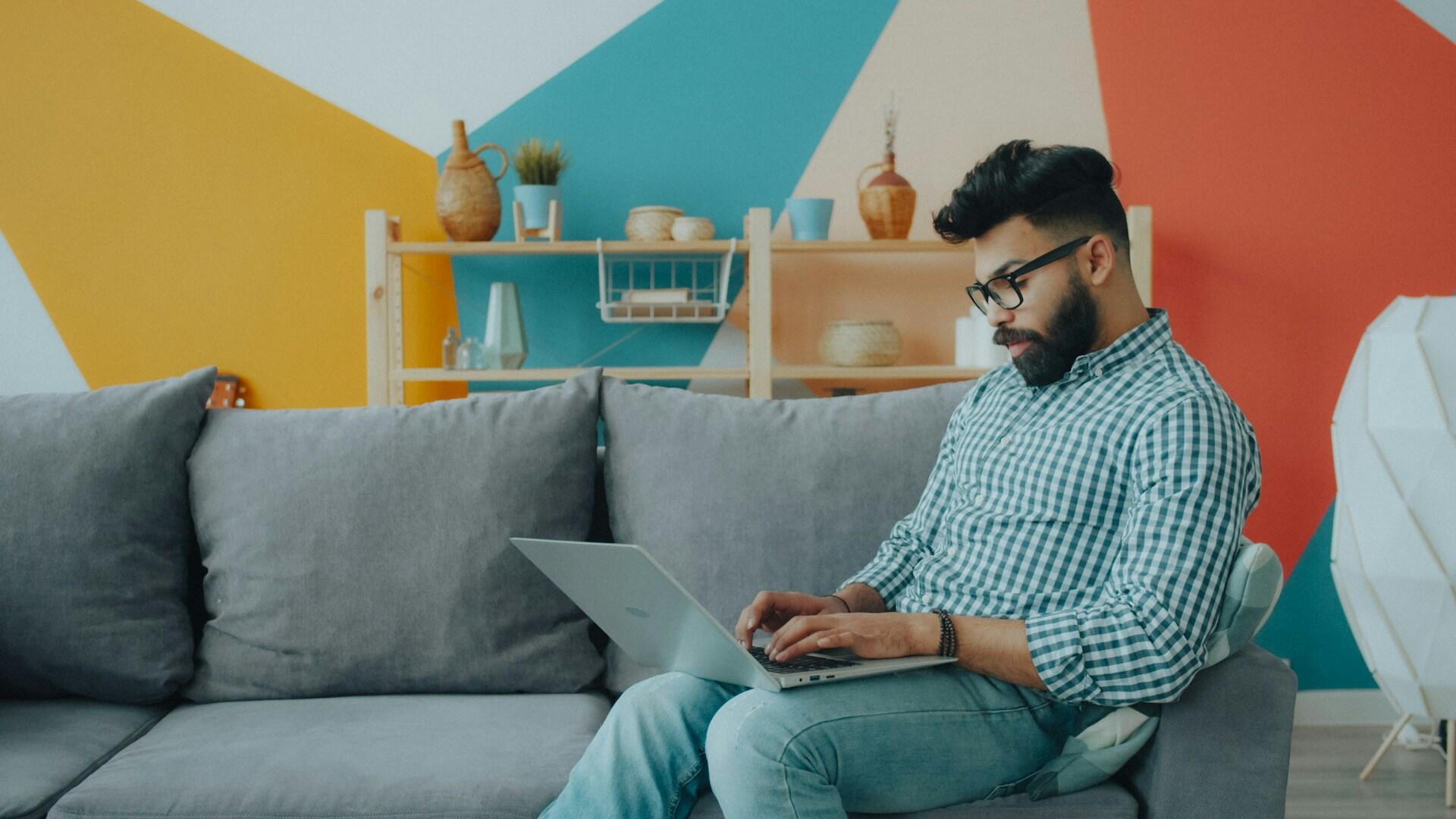 a man sitting on a couch using a laptop computer