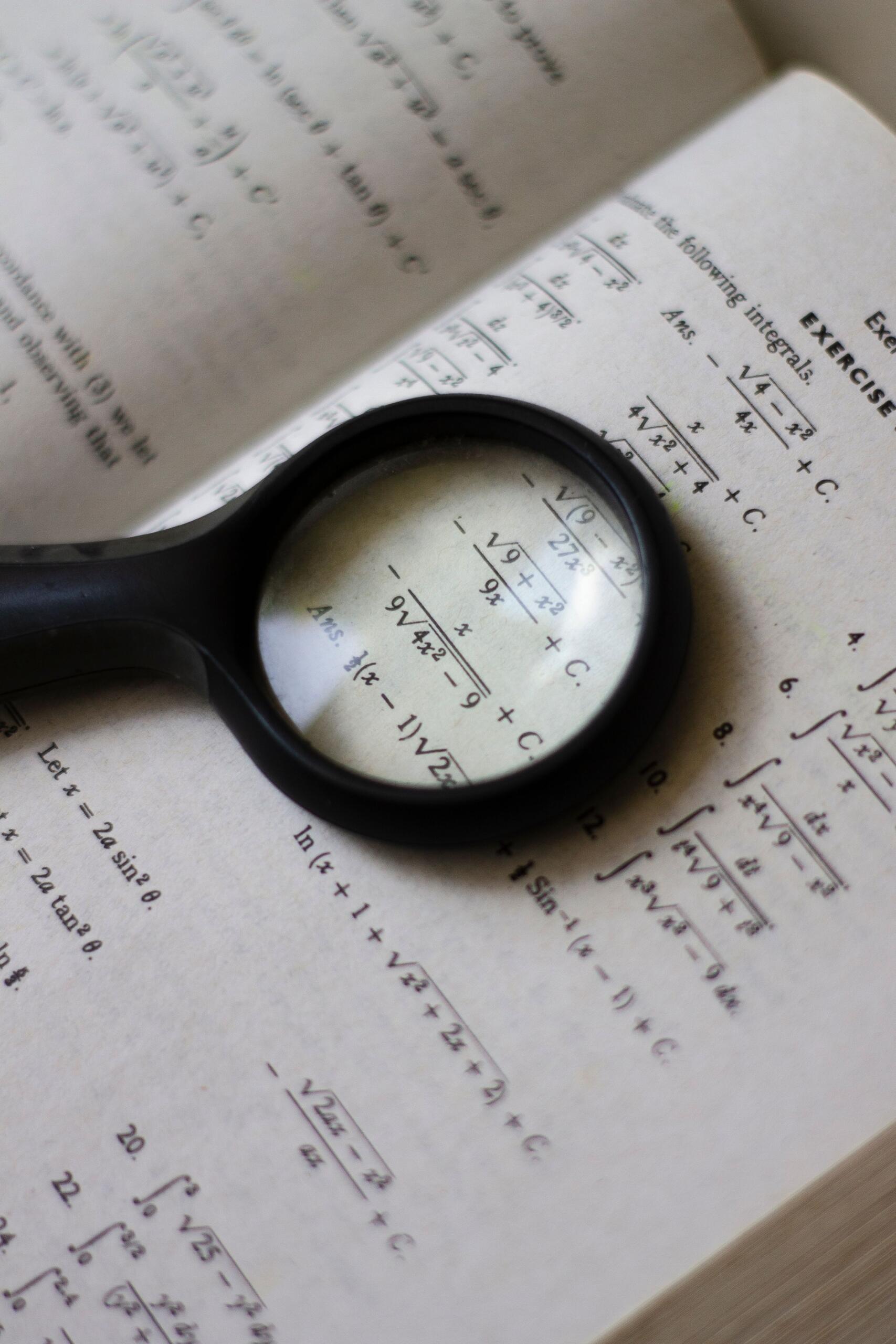 a magnifying glass on the page of a math exercise book, reflecting the importance of reading questions carefully. Source: Pexels.