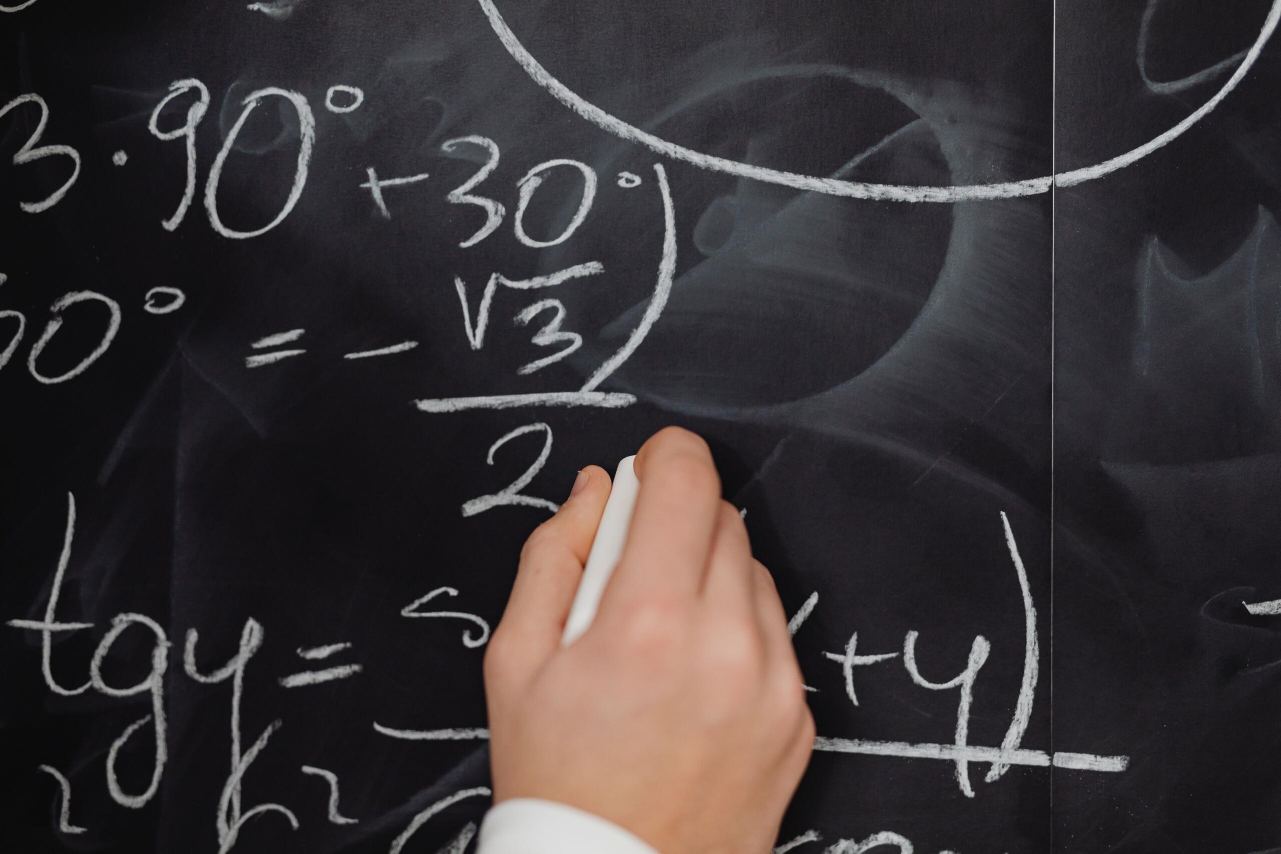a student solves a complex math equation on a blackboard.