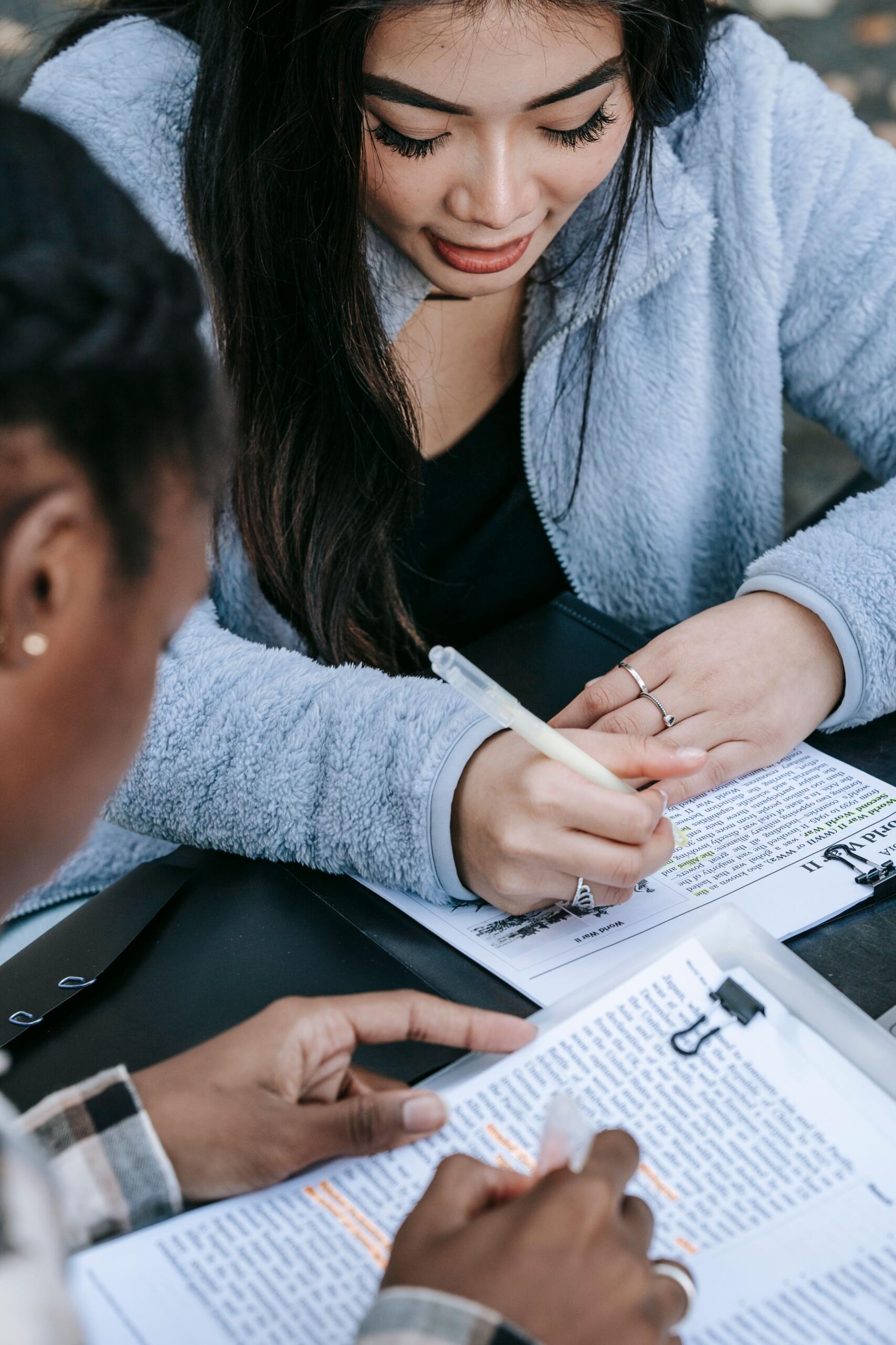 a teacher works with a student at a desk, reviewing information on a worksheet.