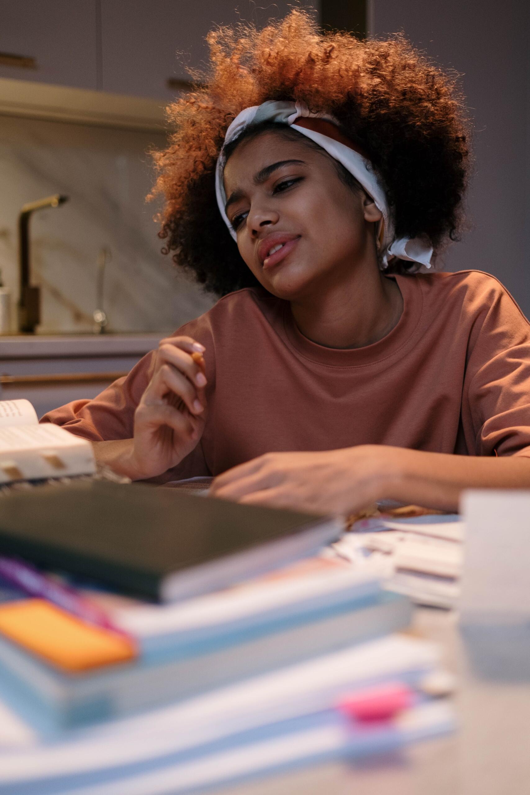 a teenage student appears stressed as she studies in front of her notebooks and textbooks.