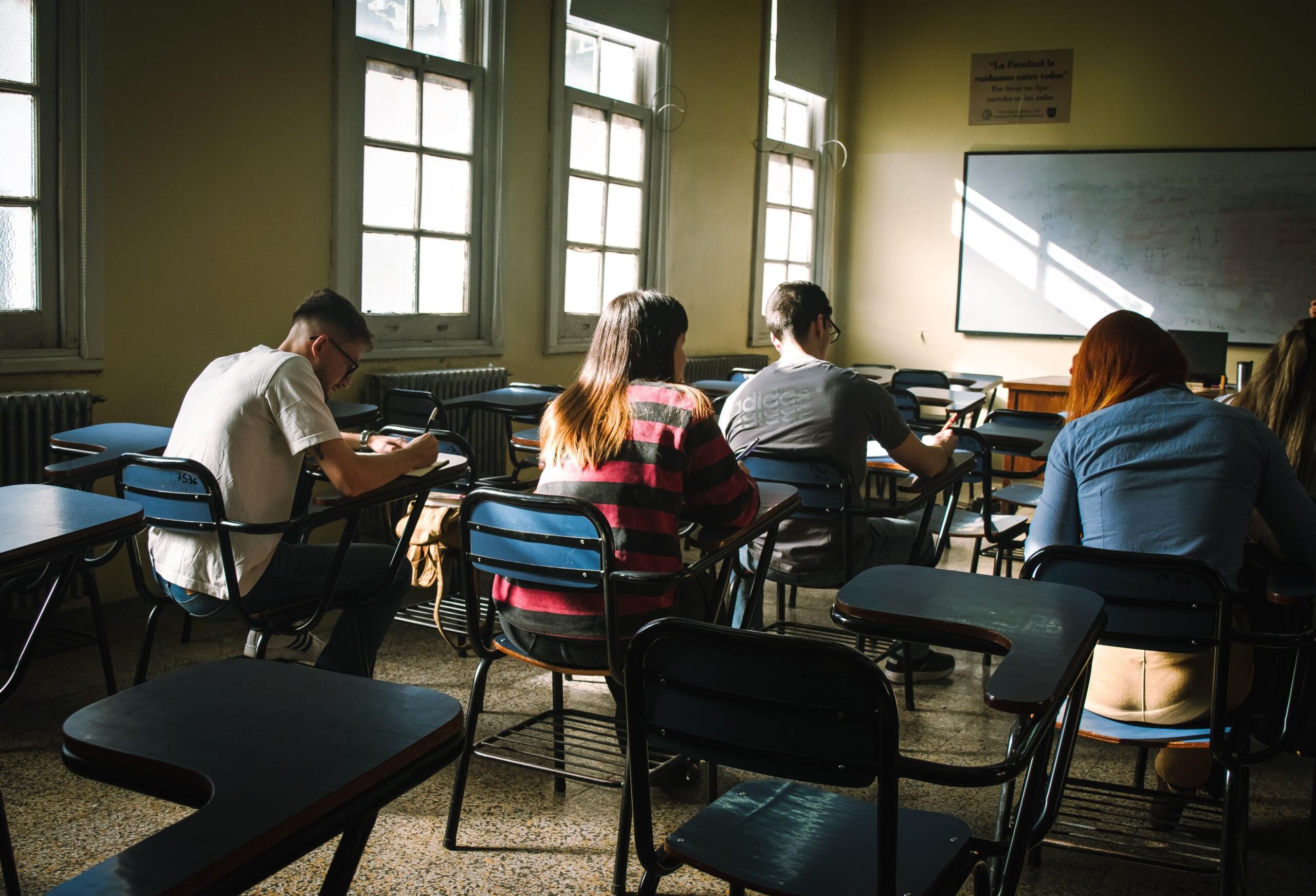 Teenage students working independently at desks in a classroom, focused on their schoolwork and learning activities.