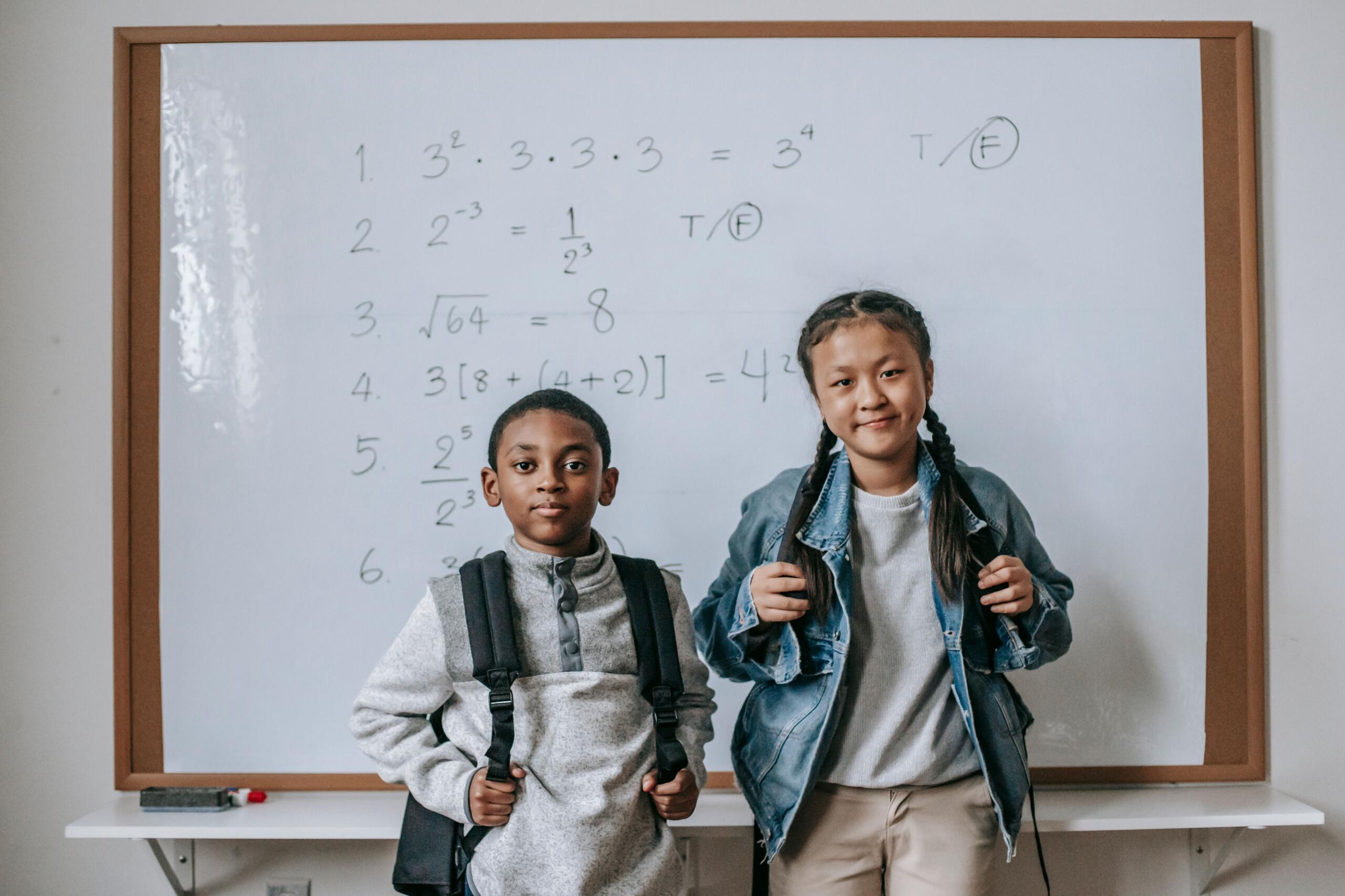 two grade six students stand in front of a whiteboard with math work written on it. Source: Katerina Holmes.