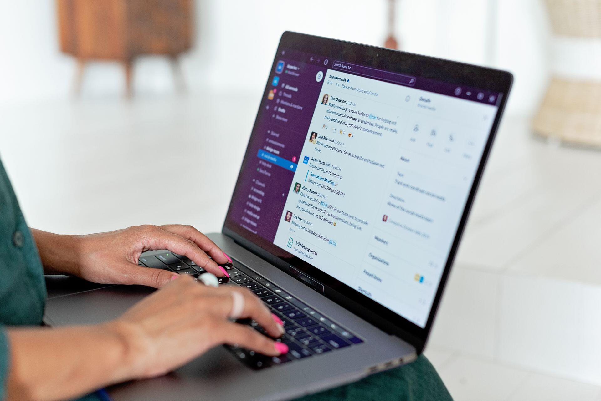 person reading and typing messages on Slack on their laptop