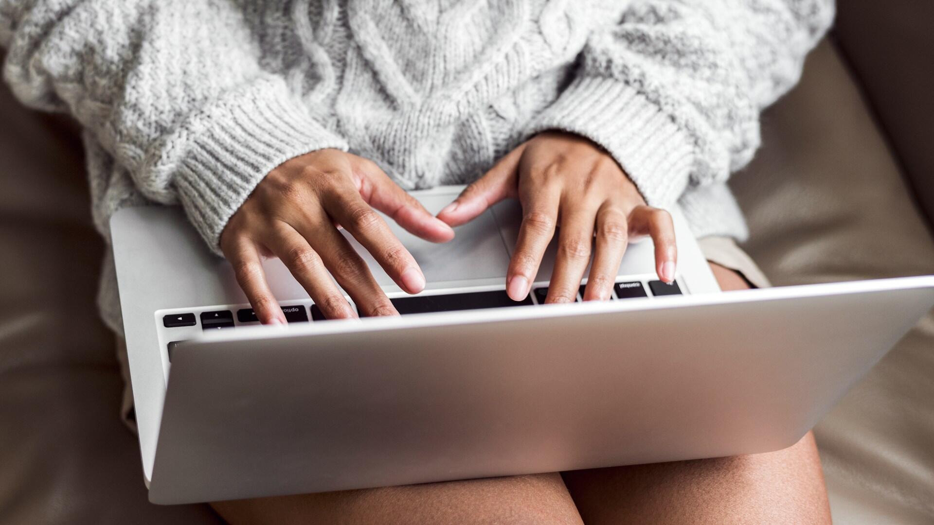 person wearing a gray sweater using a laptop computer
