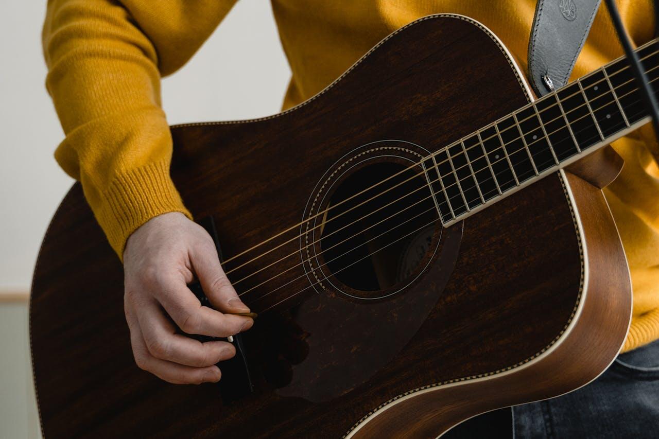 femme en pull jaune avec une guitare sombre
