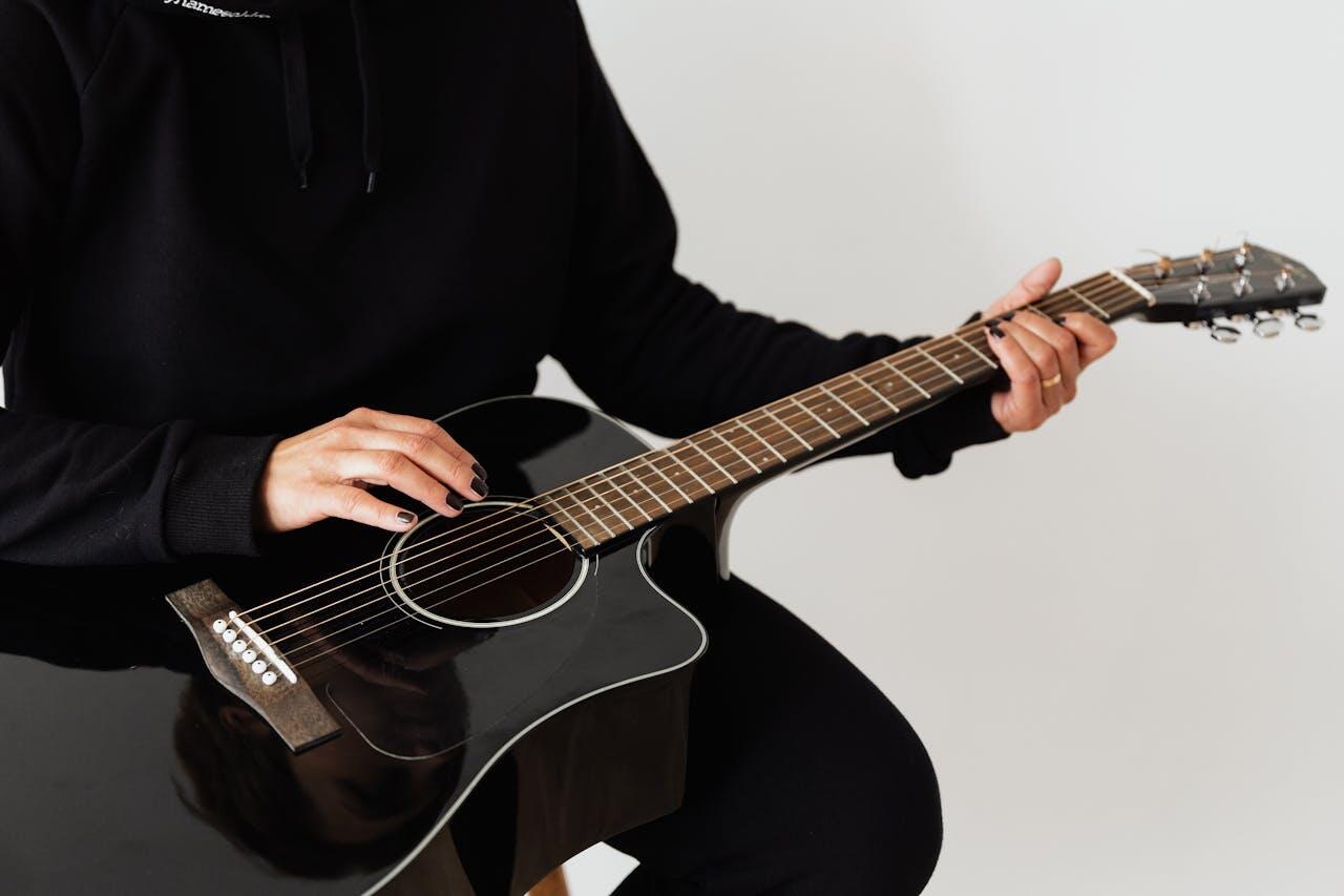 personne en noir avec guitare noir sur les genoux 