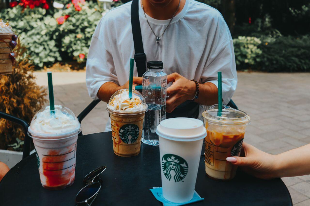 jeune a une table en exterieur avec des boissons starbucks