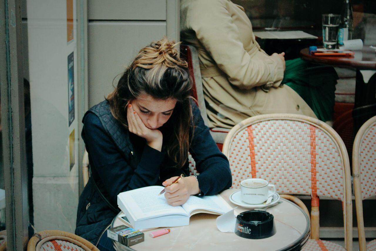 jeune femme tres concentree sur son bouquin dans un cafe