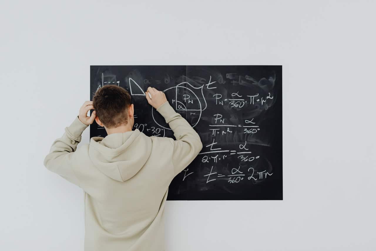 jeune homme faisant des maths sur un tableau noir