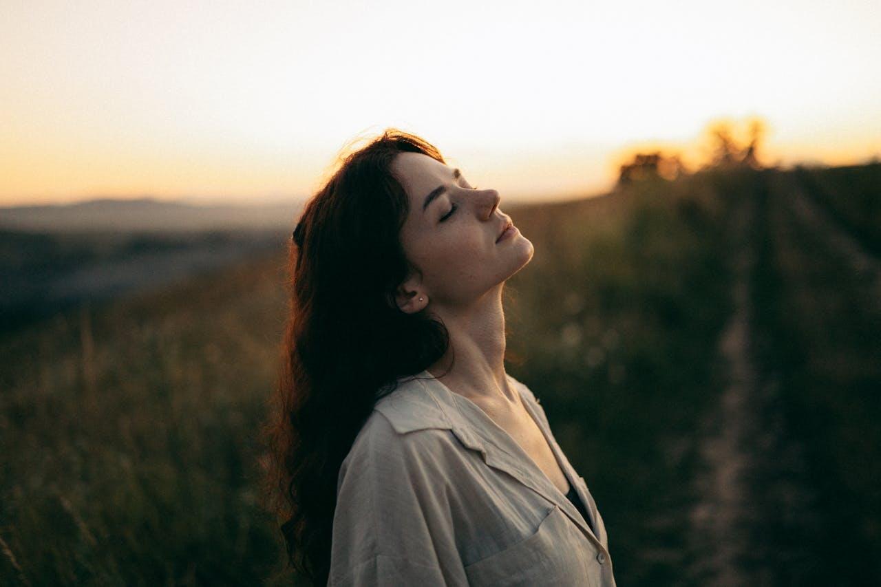 jeune femme brune dans la nature au couche du soleil fermant les yeux