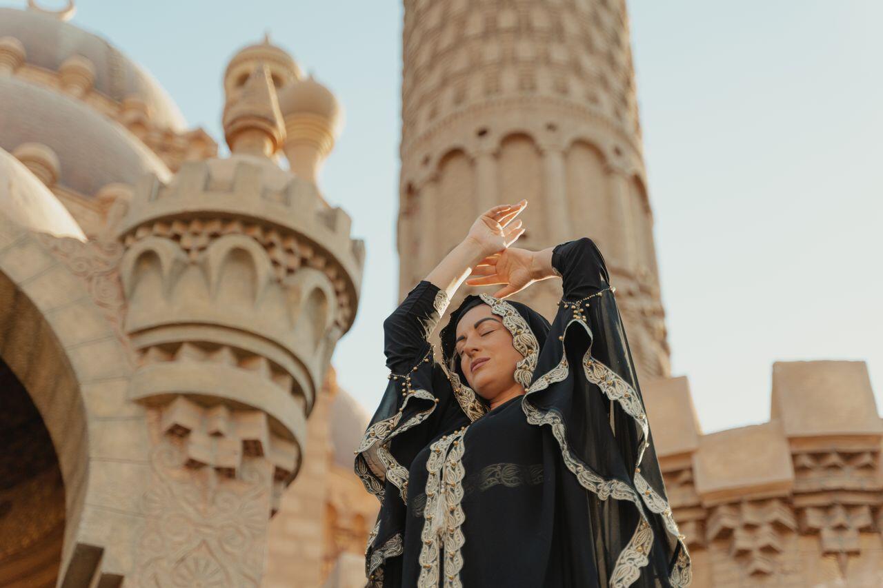 femme arabe dansant devant un batiment dans le desert