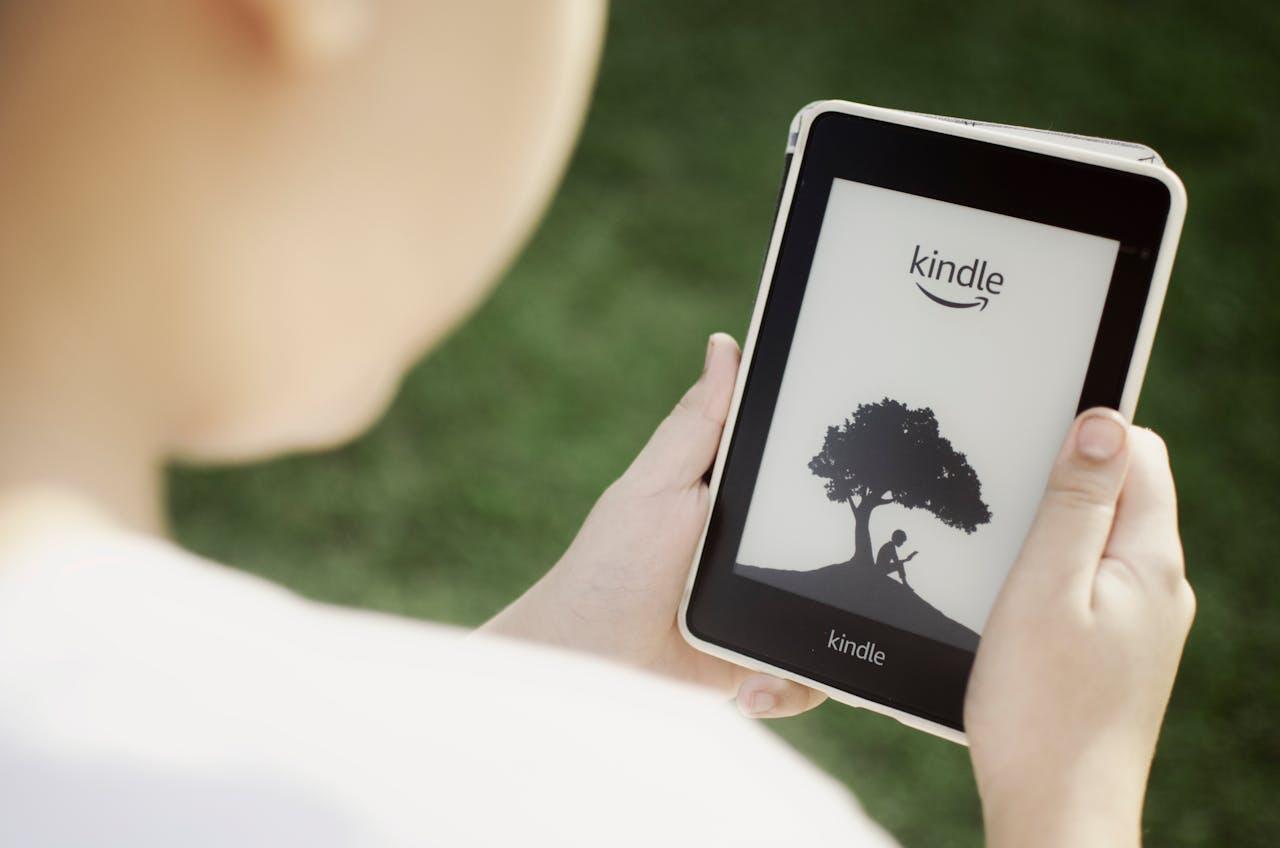 enfant tenant une kindle dans ses main dehors