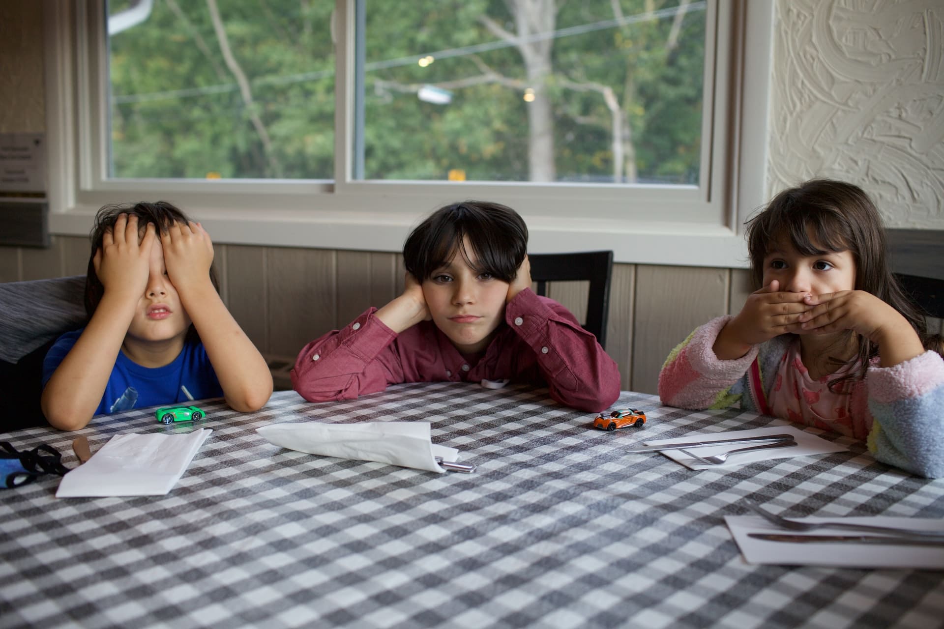 trois enfants assis a une table attendant l heure de manger