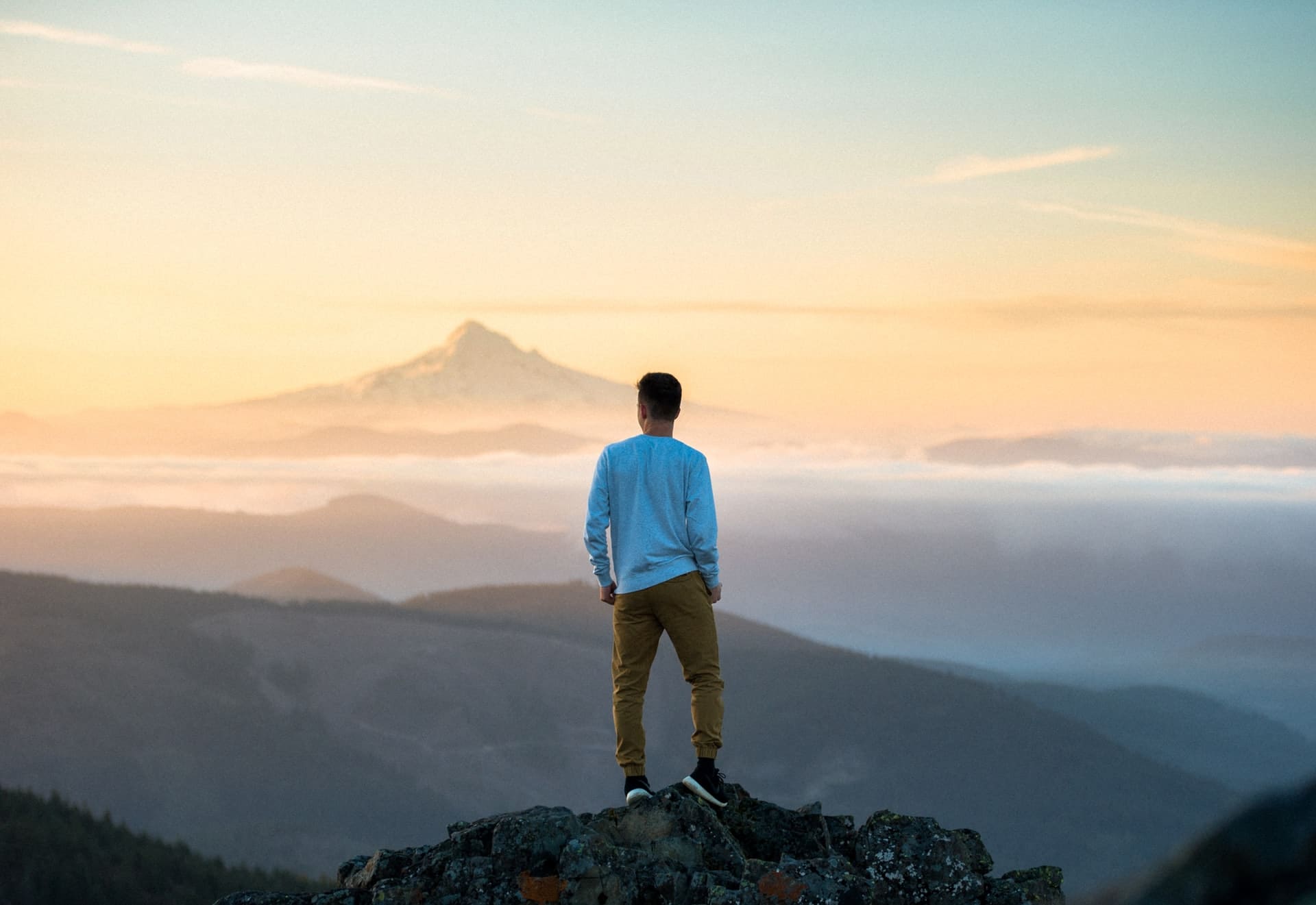 jeune homme seul contemplant les montagnes
