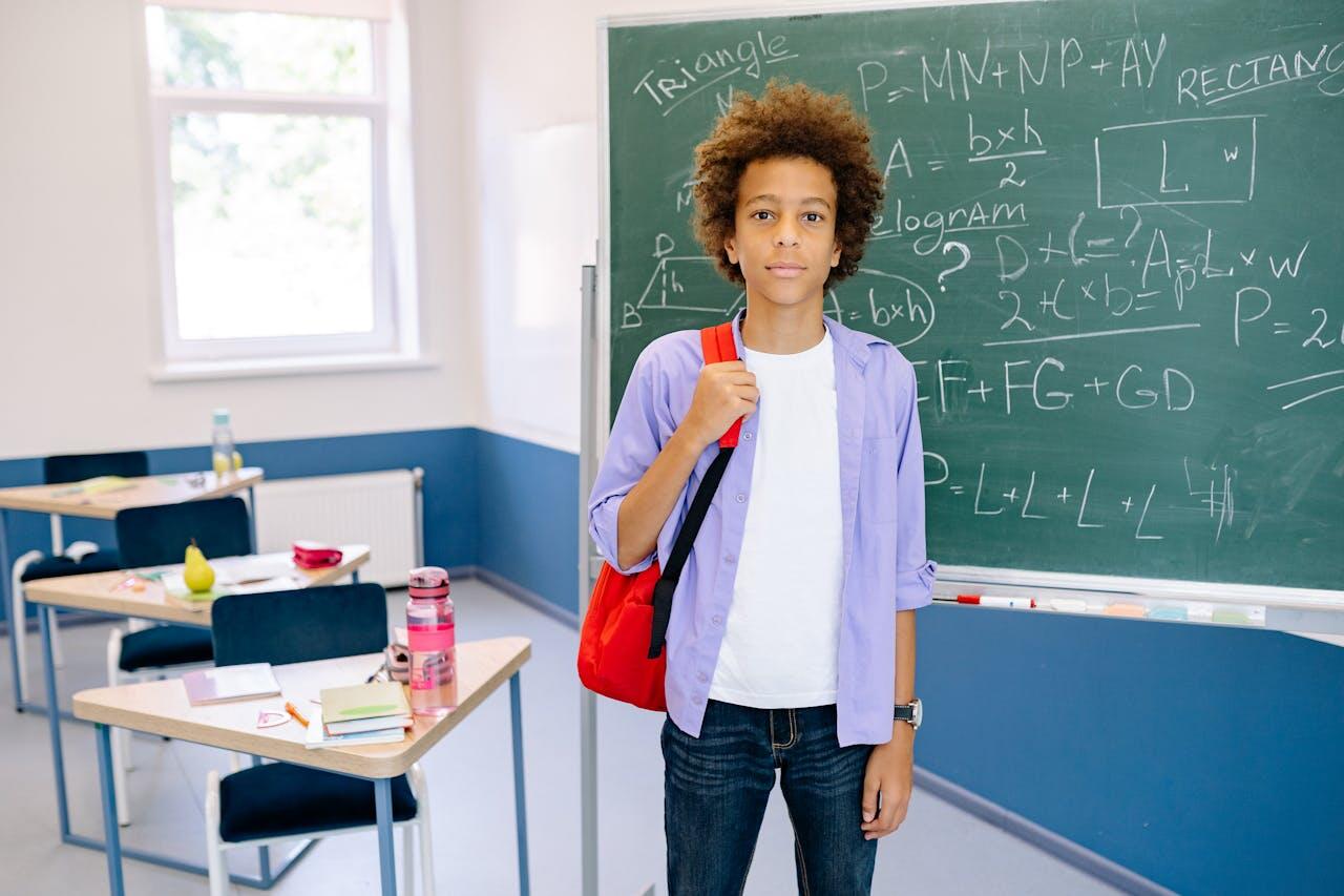 jeune garcon dans sa salle de classe dos au tableau de maths