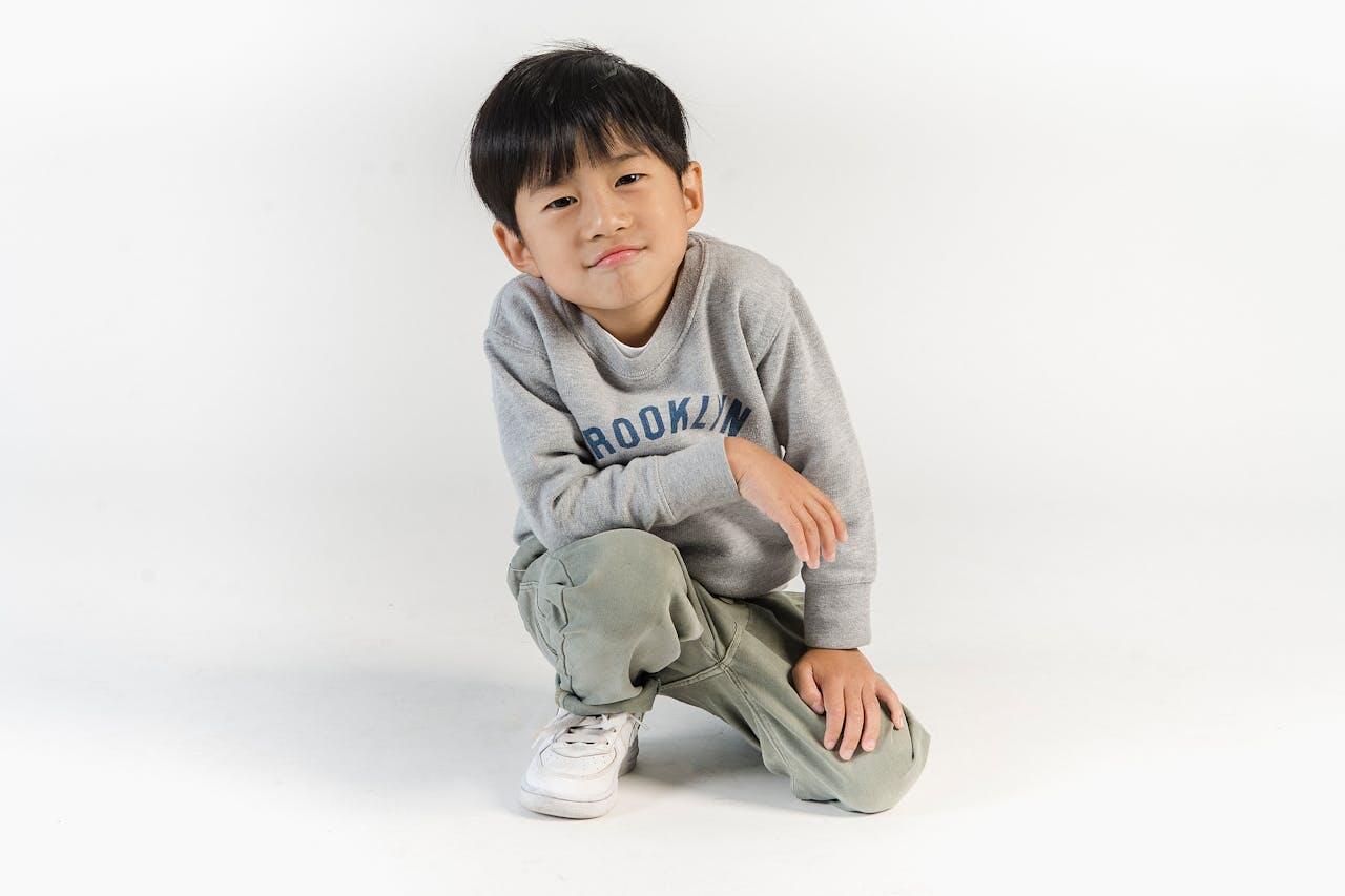 petit garcon un genou a terre en pull gris tout choupi