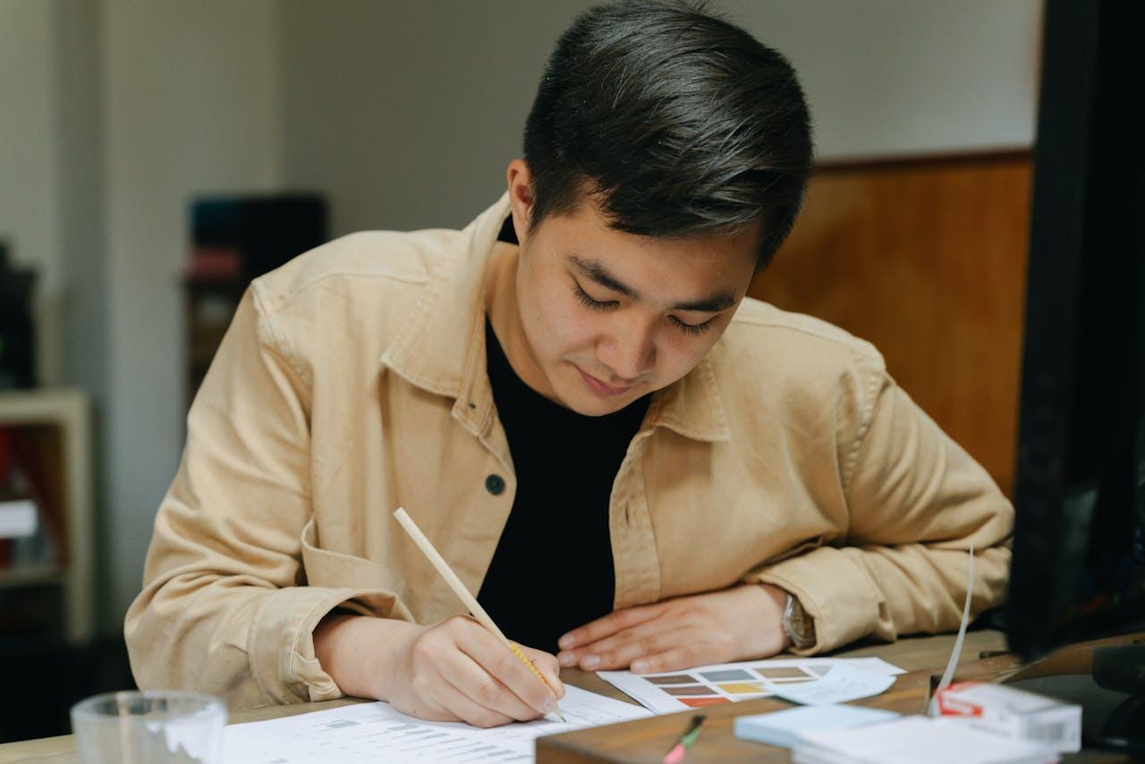 jeune homme dessinant a une table