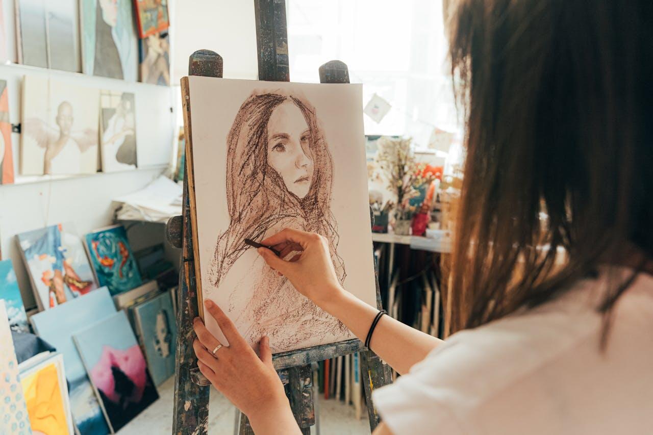 jeune femme dessinant un portrait au fusain dans son atelier