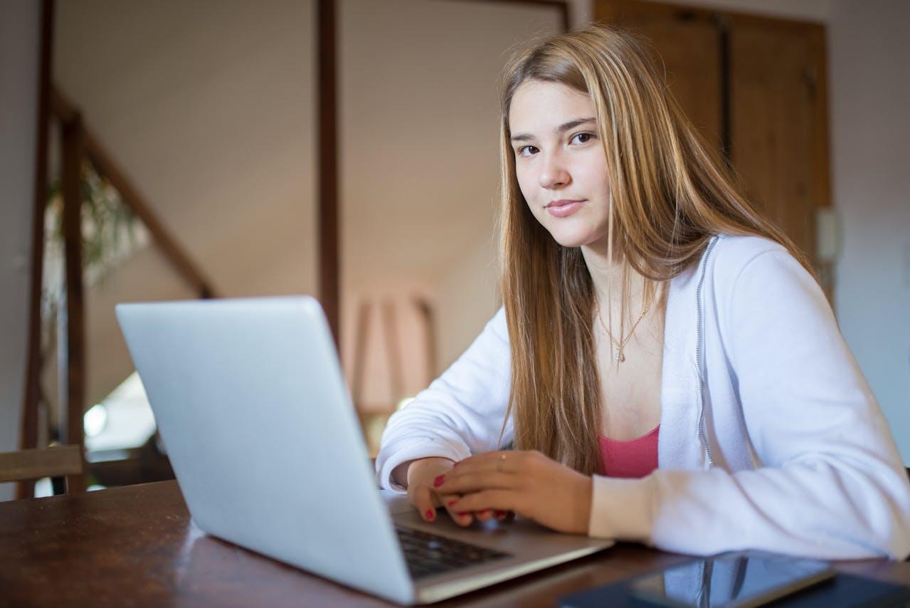 jeune ado assise sur une table regardant l objectif avec son laptop