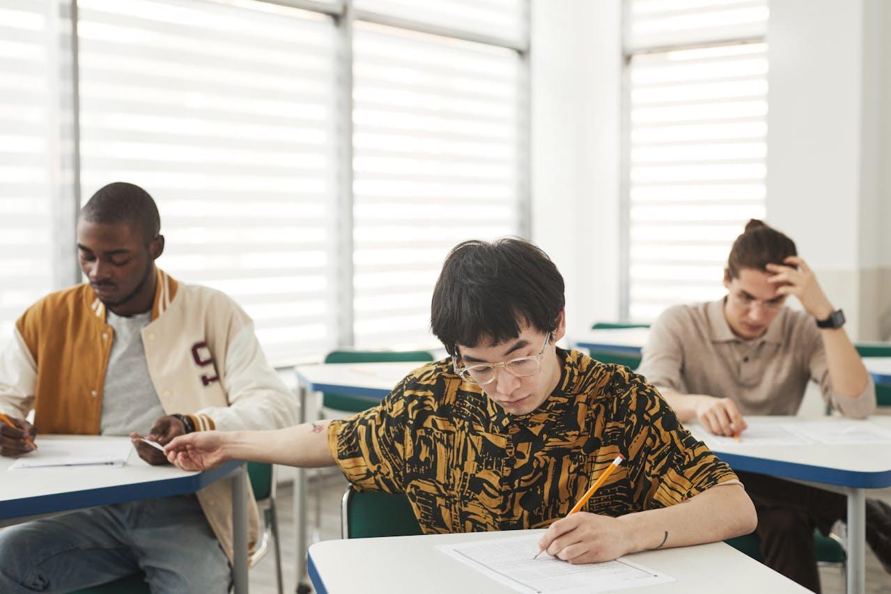 trois adolescents en classe tres concentres sur leur travail