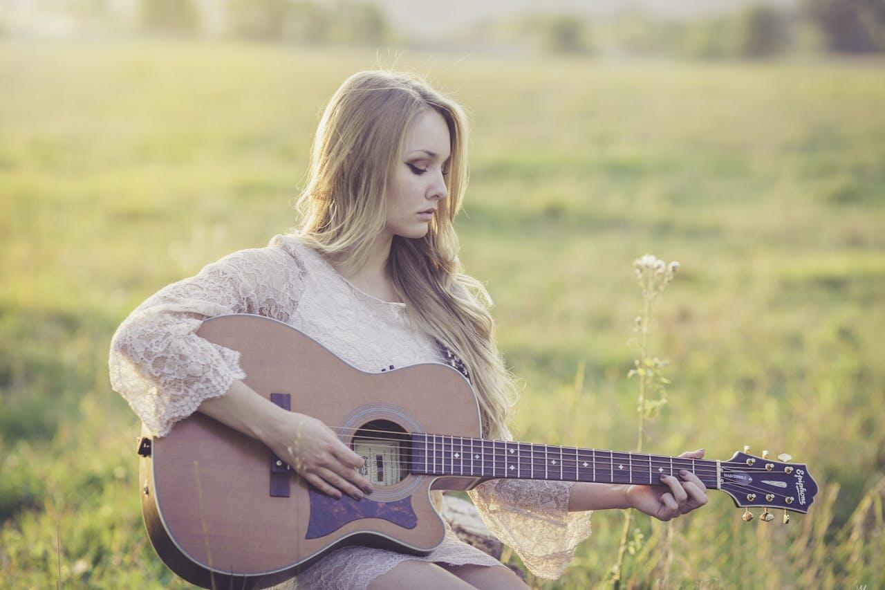 jeune femme jouant de la guitare dans une prairie